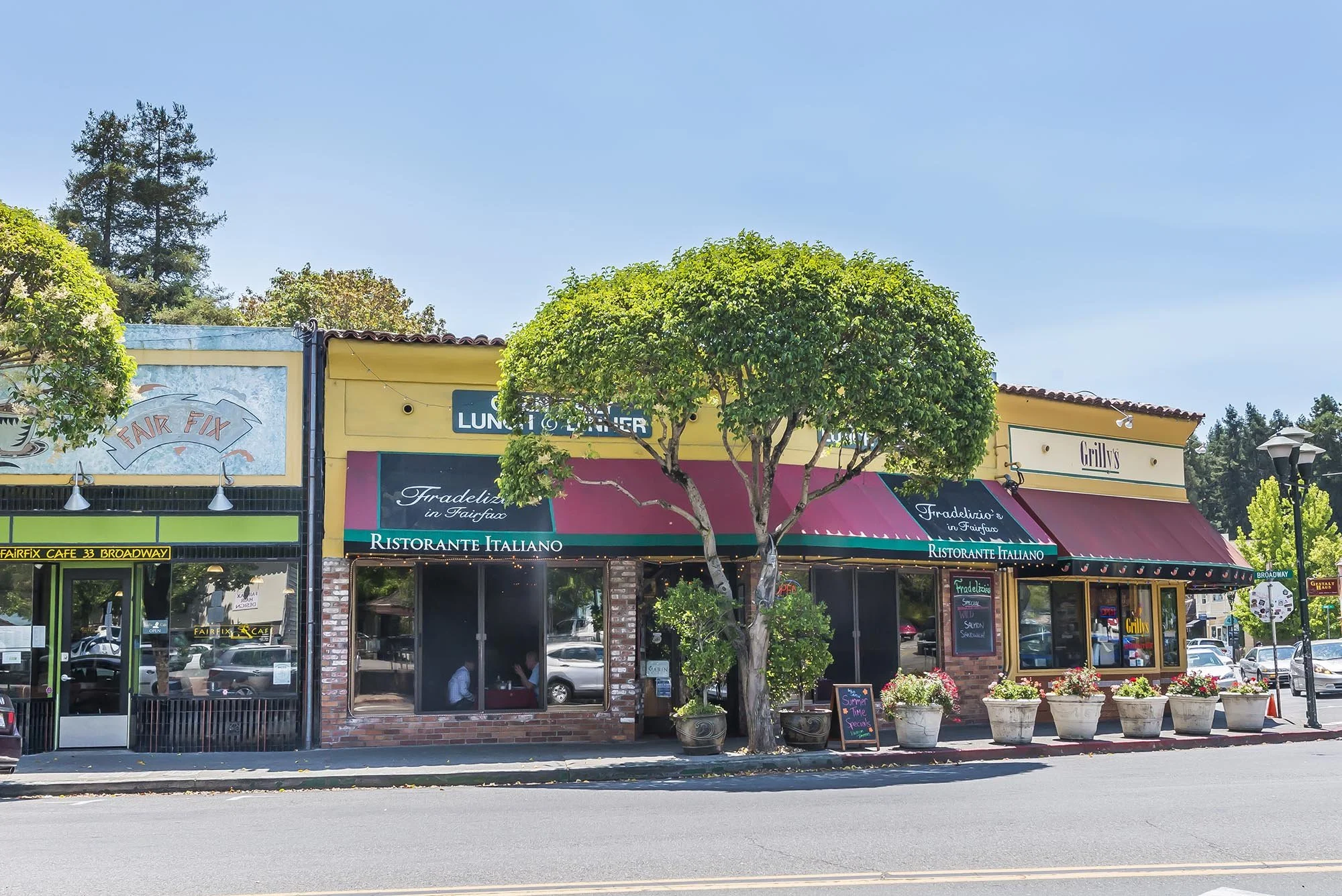 Street view of a restaurant with a yellow building, green tree in front, and potted plants outside. Signage includes "Ristorante Italiano" and "Fradelizio's in Fairfax."