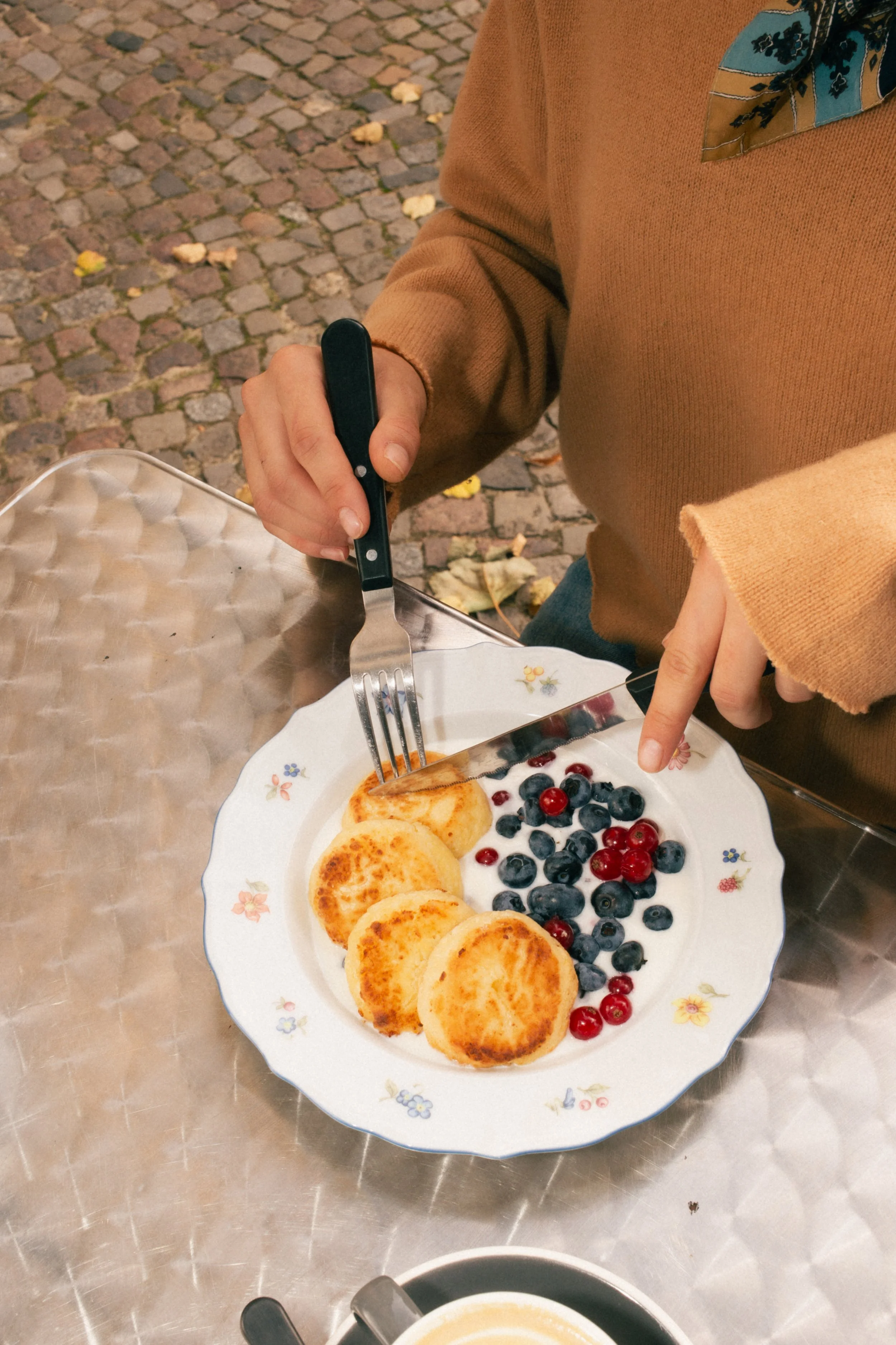 Traditional cottage cheese pancakes (syrnyky) with berry jam at a modern specialty coffee and breakfast spot in Berlin.