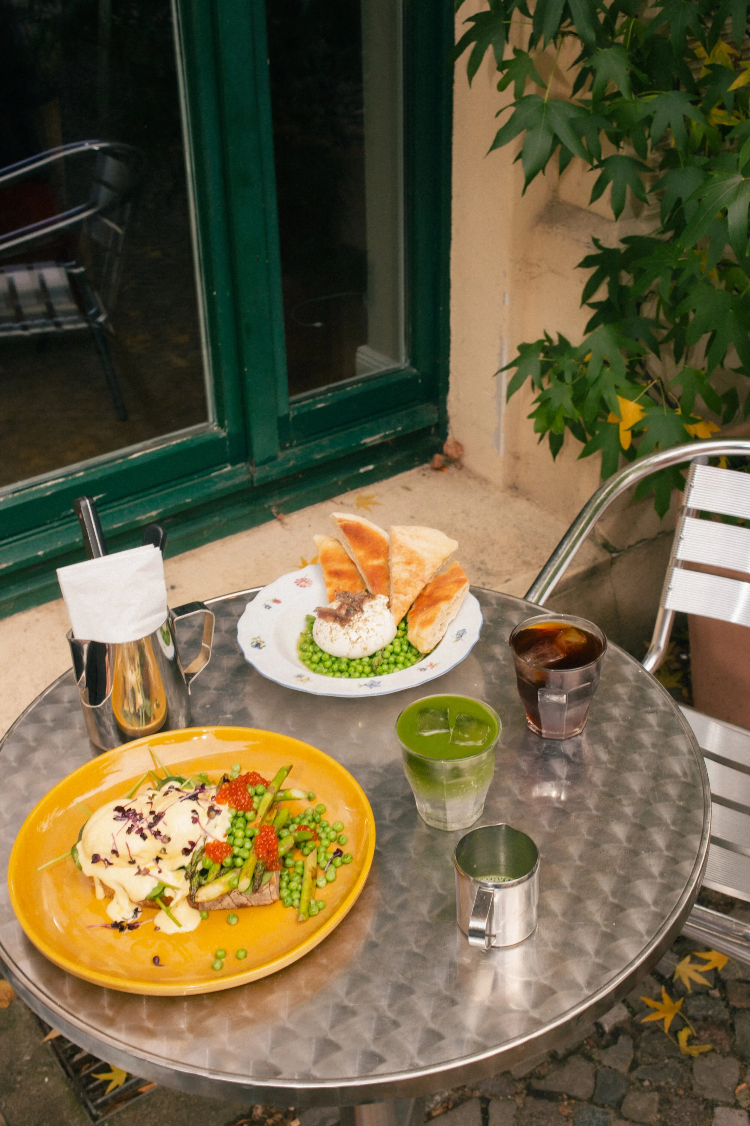 A fresh seasonal brunch dish featuring tender white asparagus, creamy burrata cheese, and young green peas, garnished with herbs at a specialty cafe in Berlin.