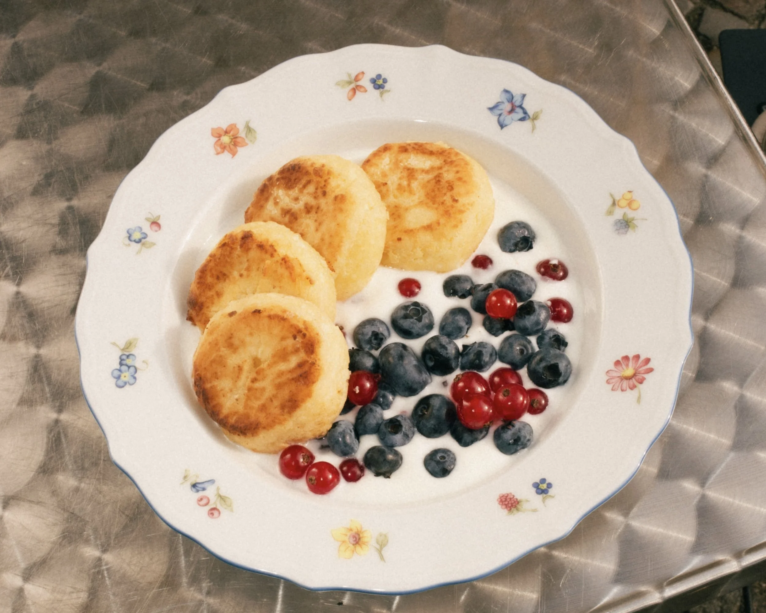Syrnyky sind kleine Cottage-Cheese-Pancakes, innen weich und außen sanft goldbraun. Es gibt sie süß mit Joghurt, Karamellsauce und Beeren