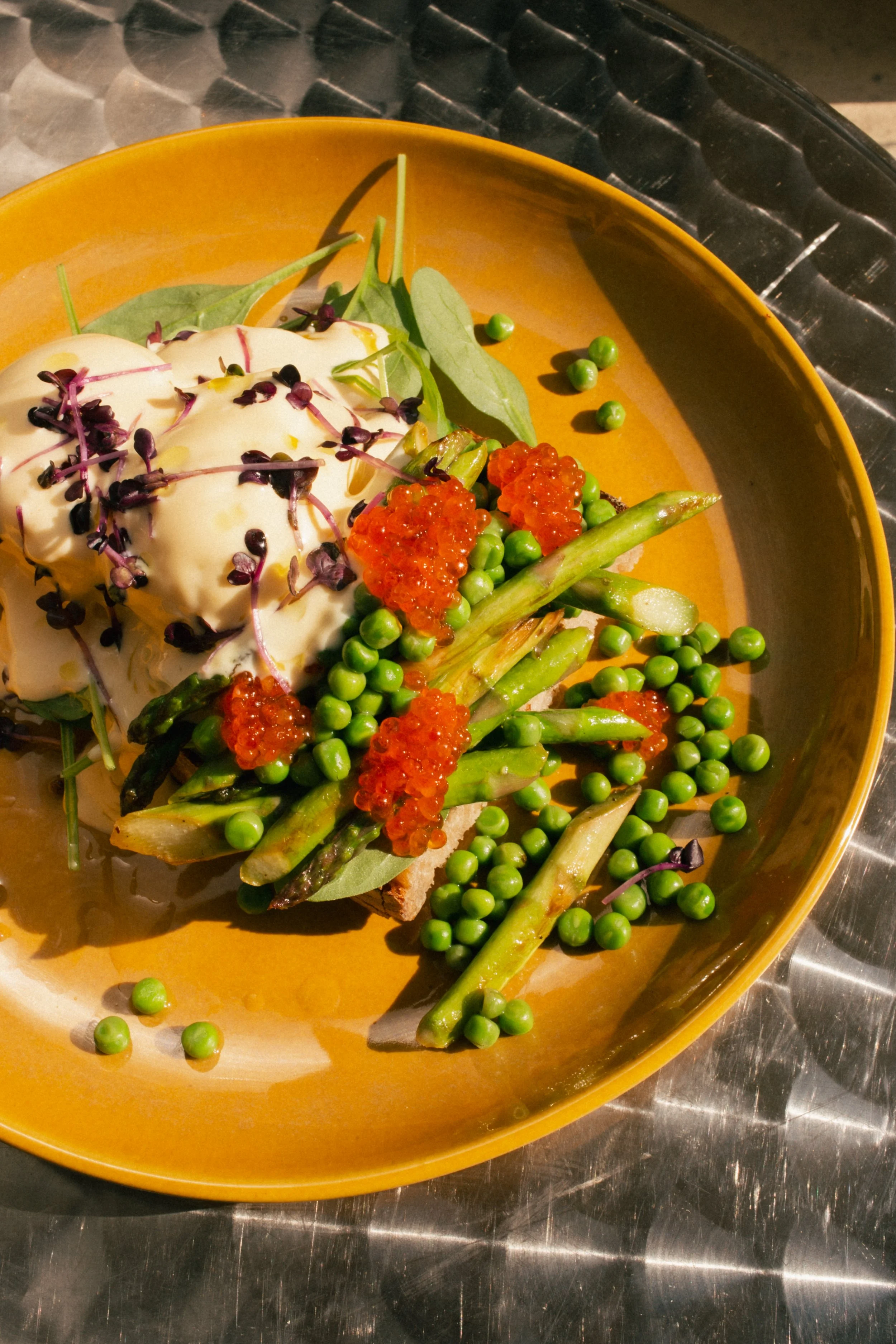 Enjoy the top seasonal brunch in Berlin: grilled green asparagus with fresh peas and creamy dressing, served on a sunlit outdoor terrace at our specialty cafe.