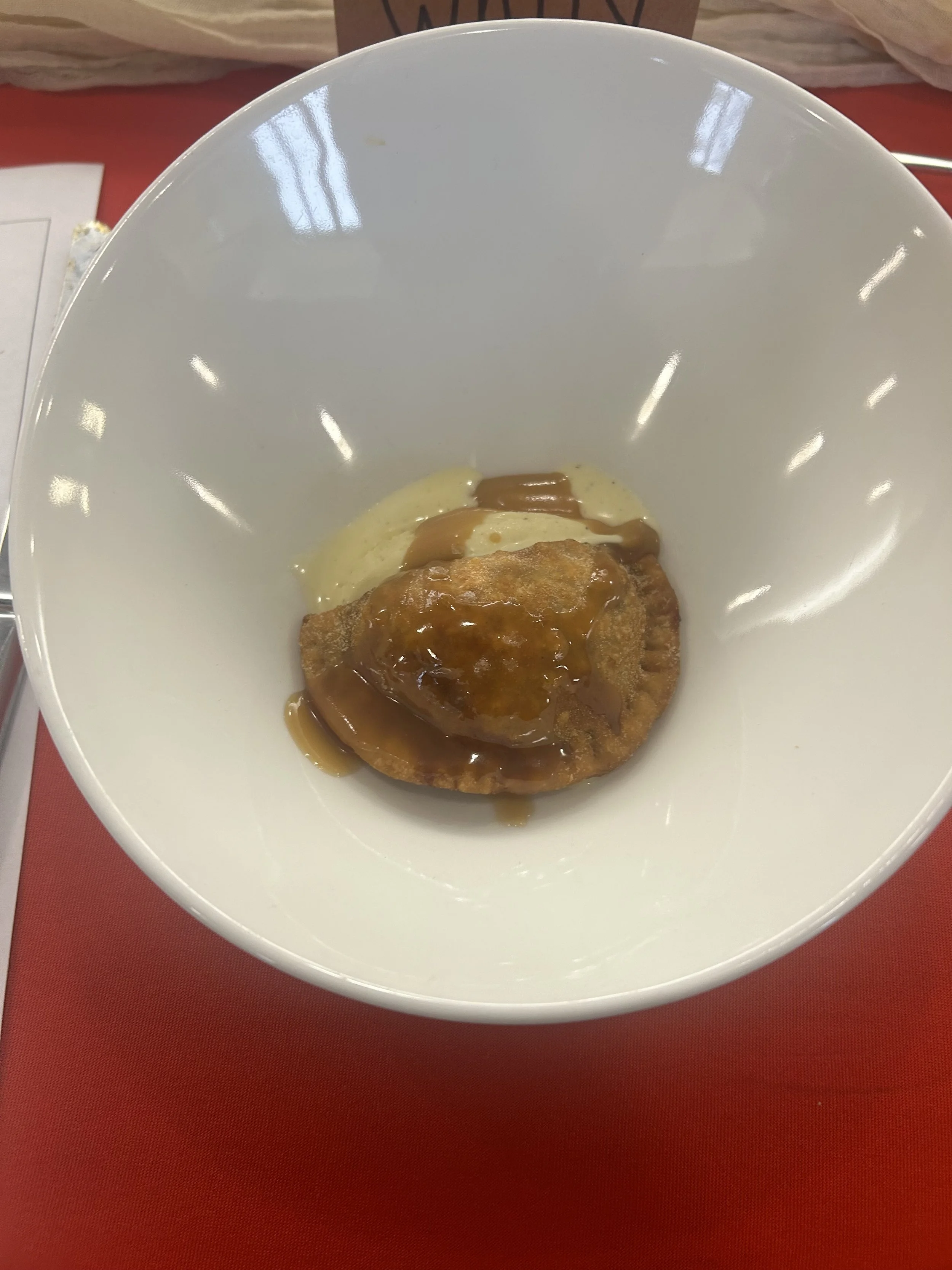 A bowl containing a piece of cooked meat topped with gravy, served with a side of mashed potatoes.