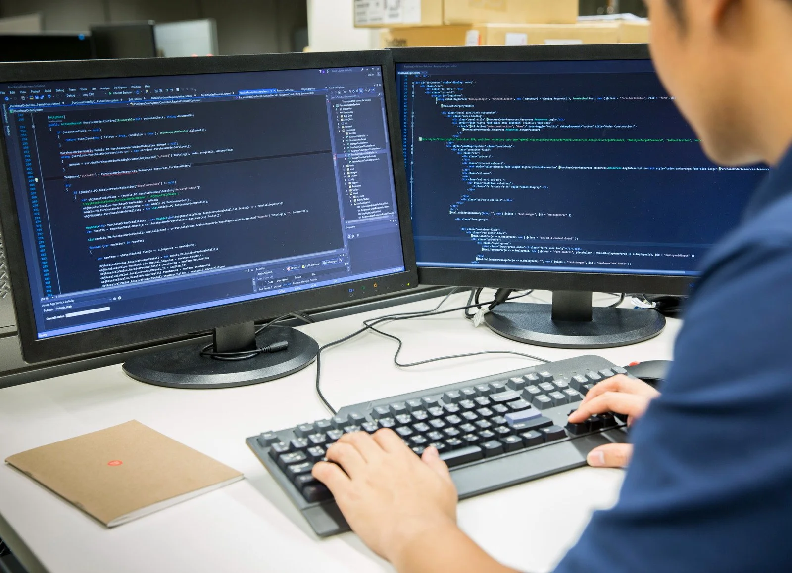 software engineer working with source code (programming) on two monitors
