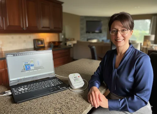 Woman sitting in her home using a laptop to analize her health scan with biopulse reader.