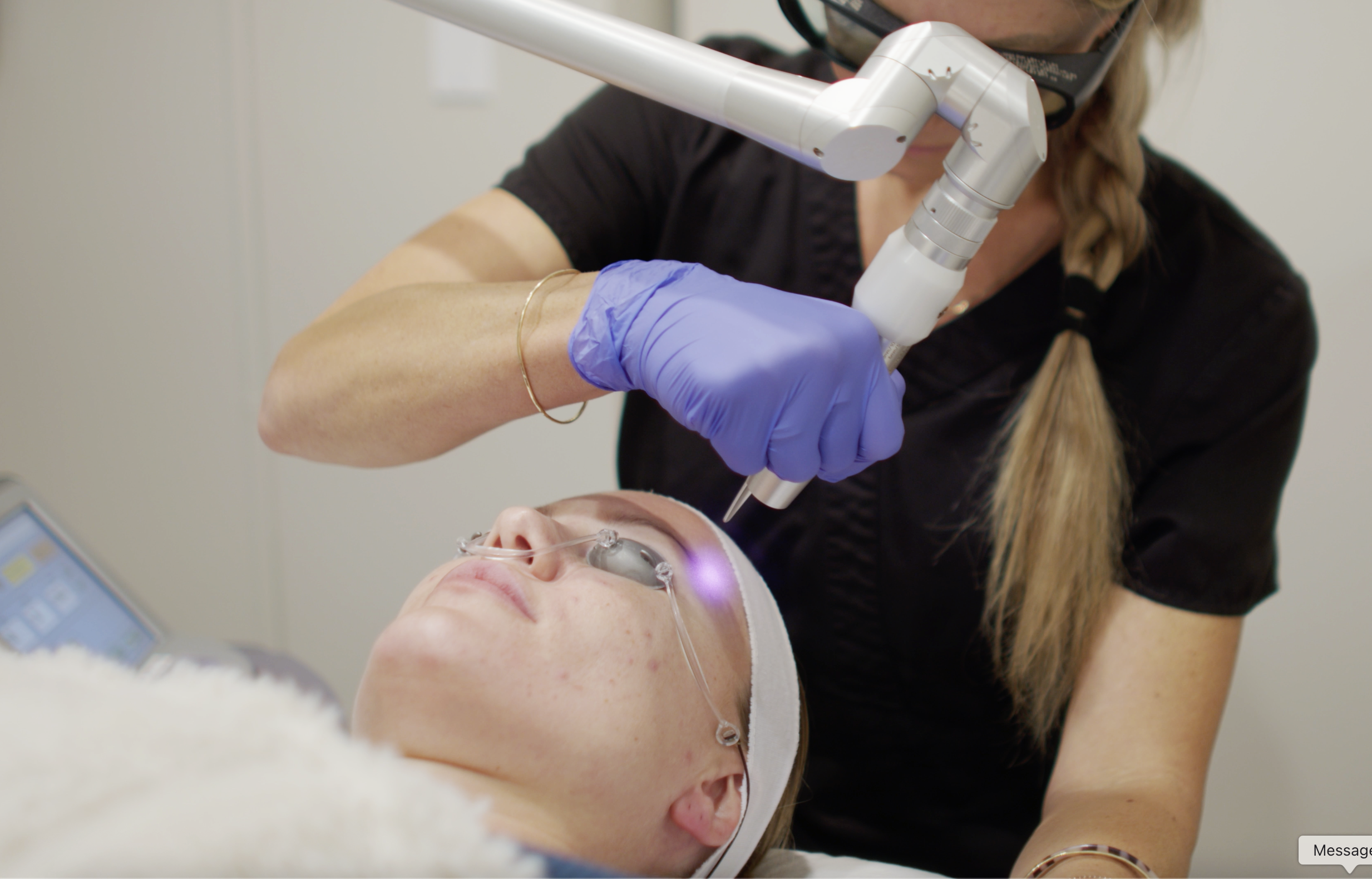 A dentist or dental specialist performing a procedure on a patient using a laser or dental tool, with both individuals wearing protective gear.