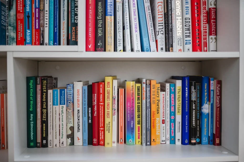 Photo of a white bookshelf with two shelves filled with various books.