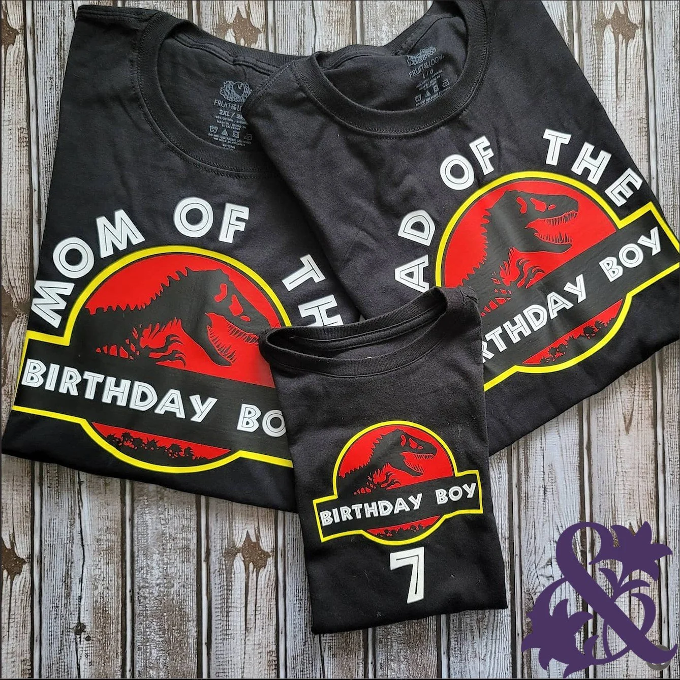 Three matching black dinosaur birthday shirts with red, yellow, white, and black designs