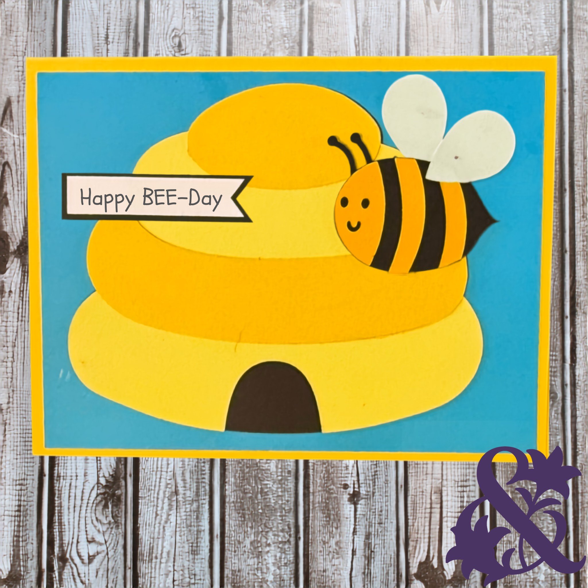 Handmade birthday card featuring a smiling bee, yellow beehive, blue background, and Happy Bee-Day message