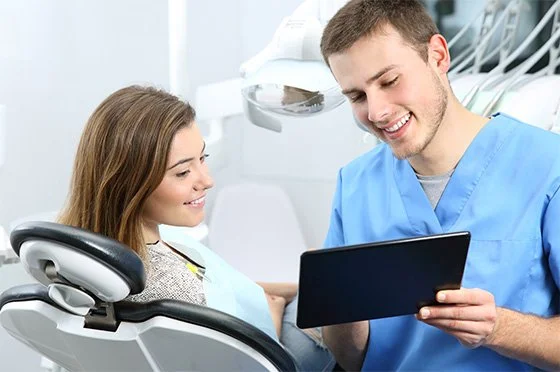 Dentist showing a patient information on a digital tablet during a periodontal consultation.