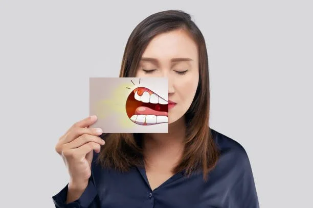 Woman holding a picture of an inflamed gum illustration in front of her face to represent gingivitis symptoms