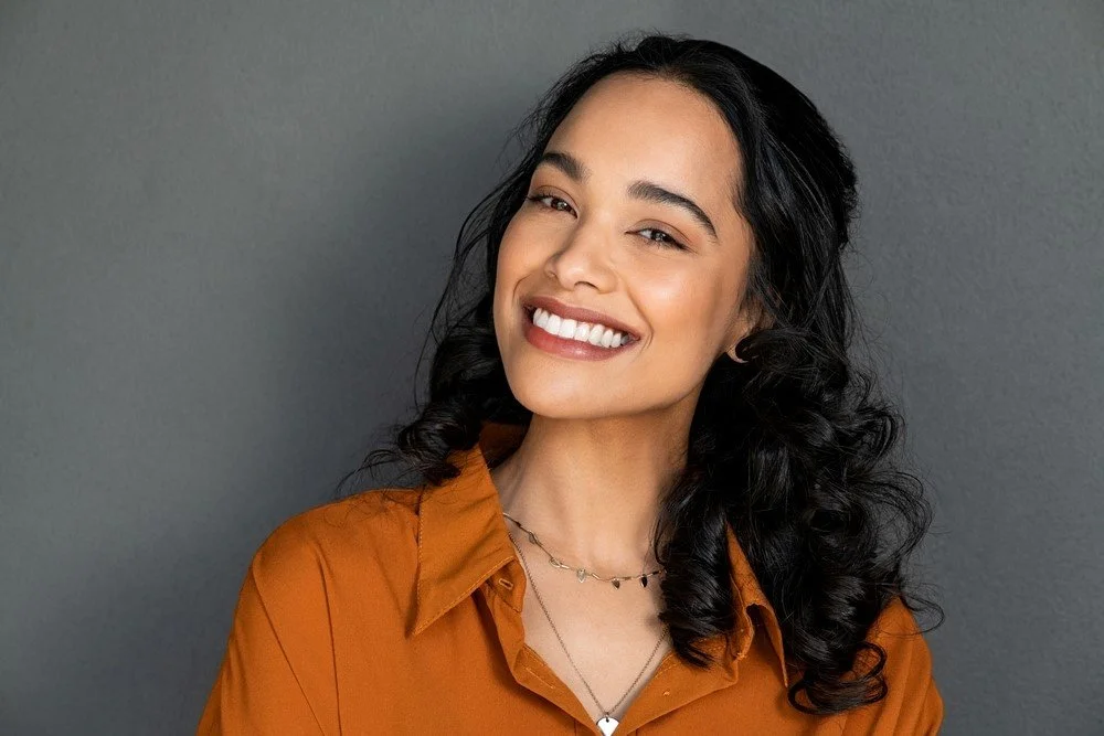 Smiling woman representing the benefits of preventive dentistry treatments like dental sealants and fluoride for long-term oral health.
