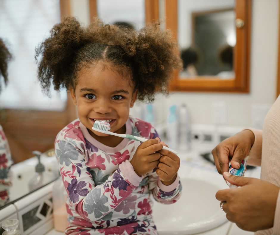 Child brushing teeth with the help of a parent in a bathroom, promoting good oral hygiene before silver diamine fluoride treatment