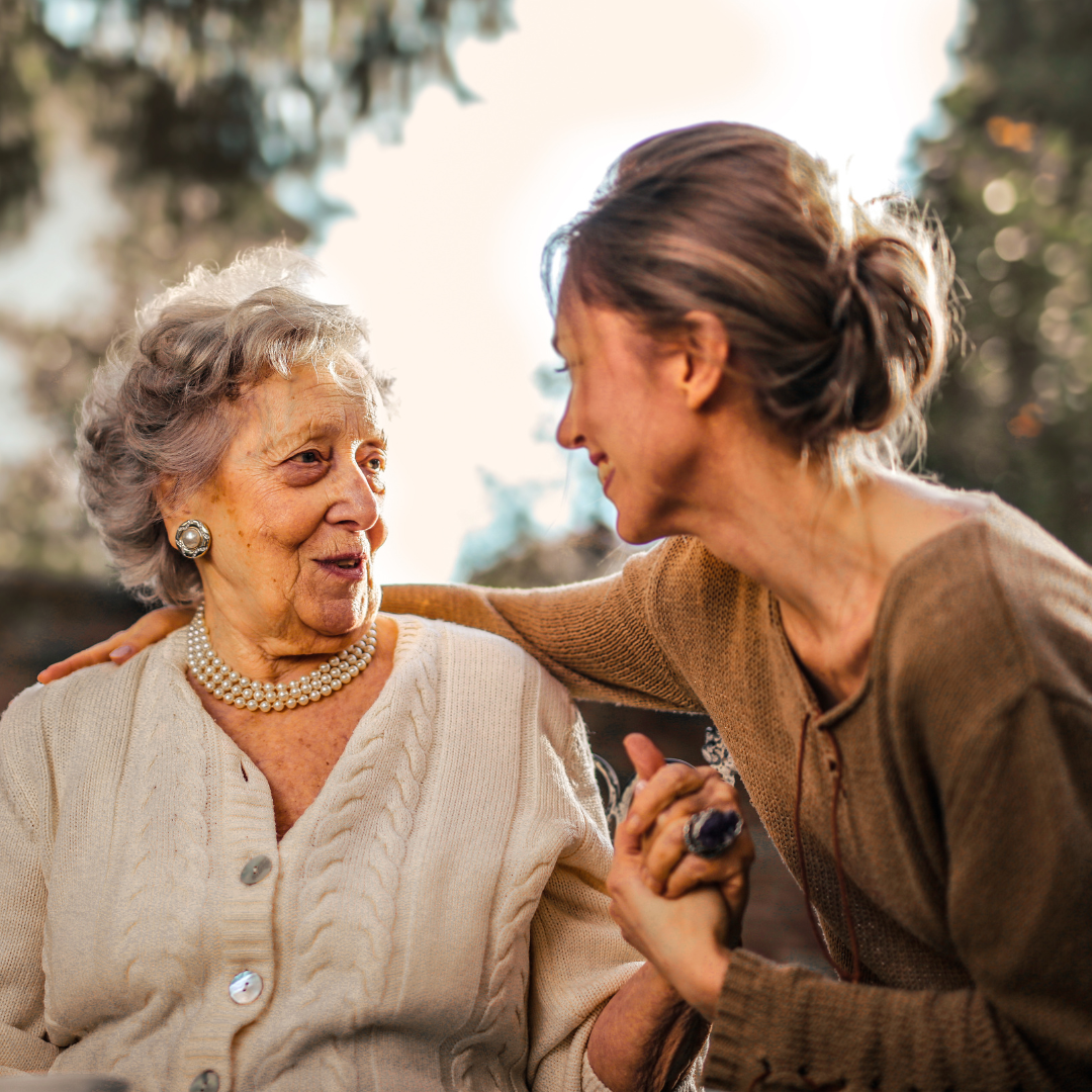 Young woman talking closely with an older woman outdoors, illustrating how bad breath can affect personal interactions
