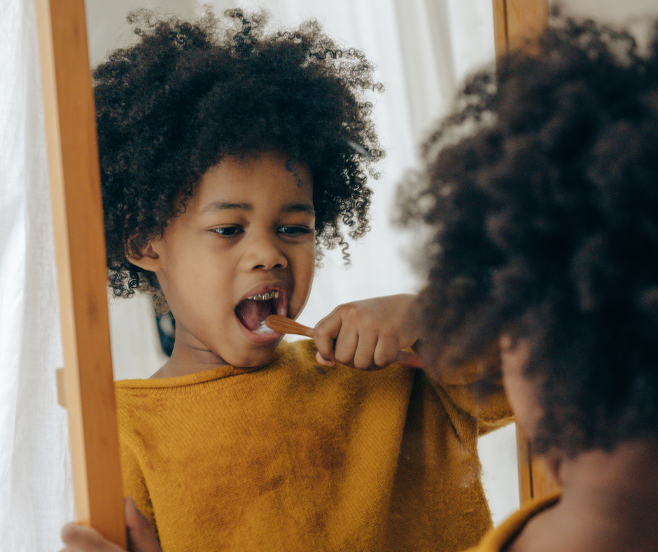 Young child brushing teeth while looking into a mirror.