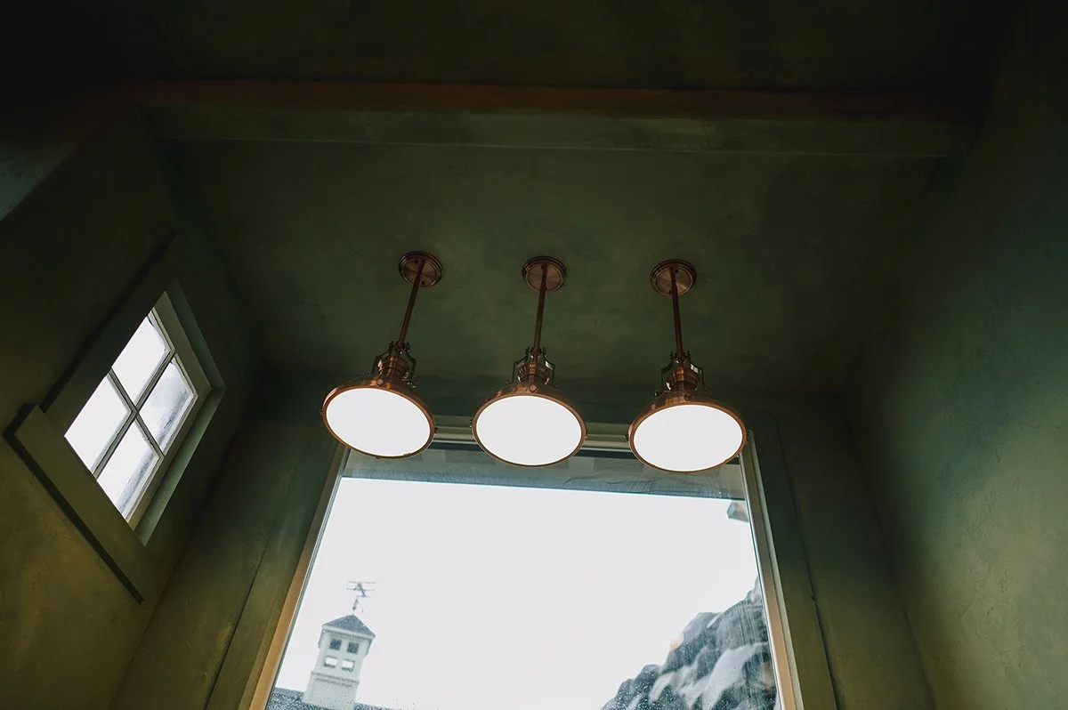 Copper pendant light installation inside a remodeled garden shed workspace.