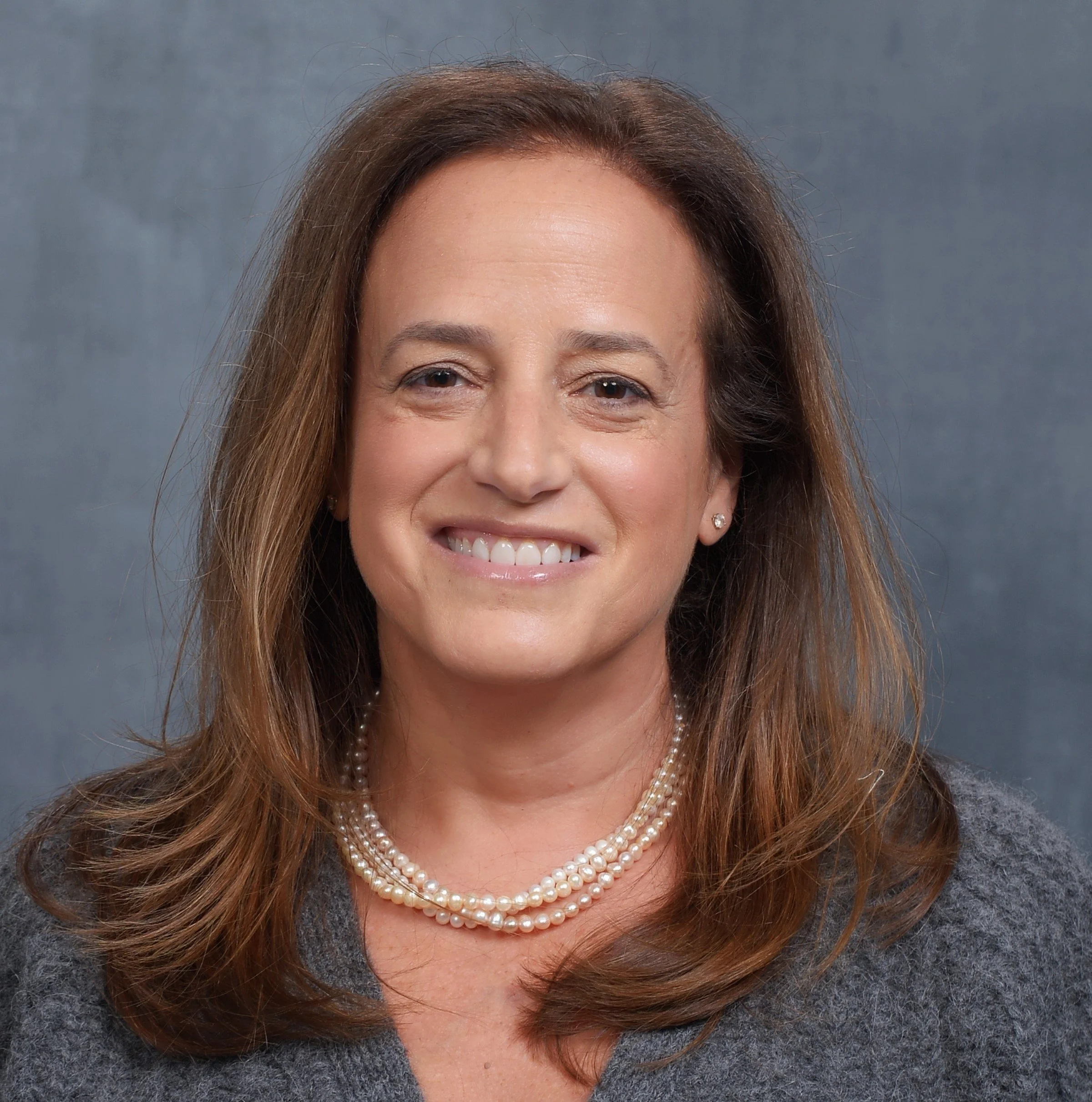 A woman with brown curly hair smiling at the camera.