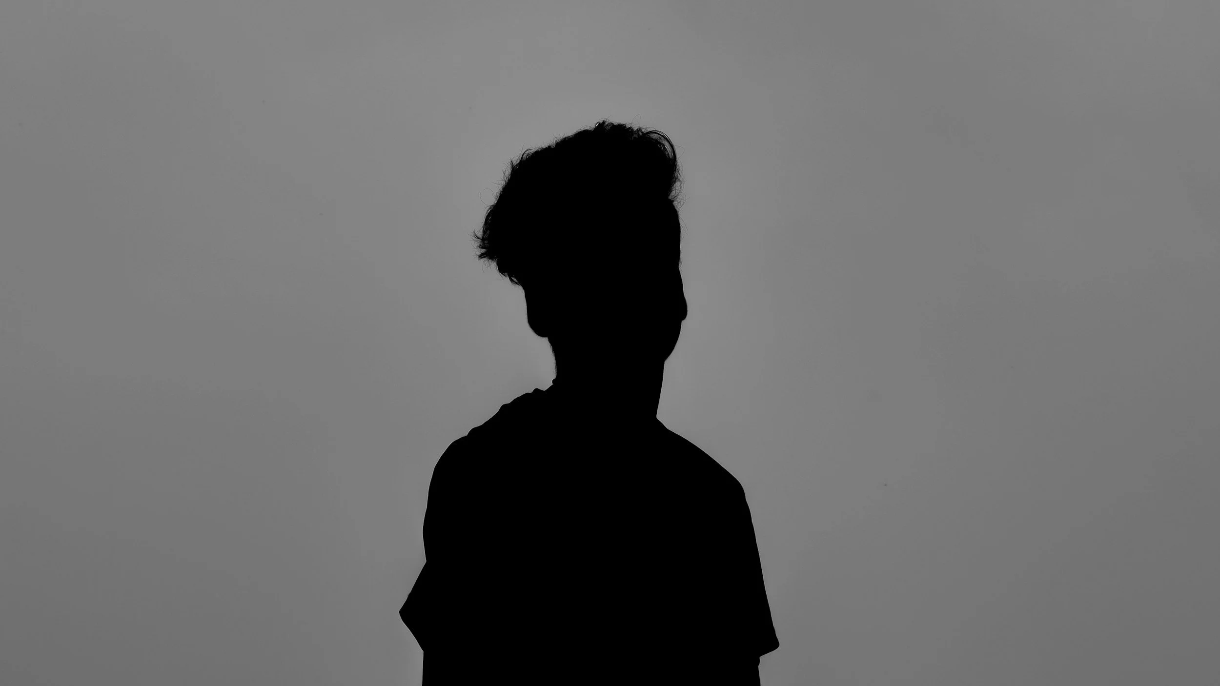 Silhouette of a person with short hair against a plain background.