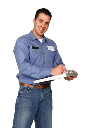 A man in a blue work uniform holding a clipboard and pen, smiling at the camera.
