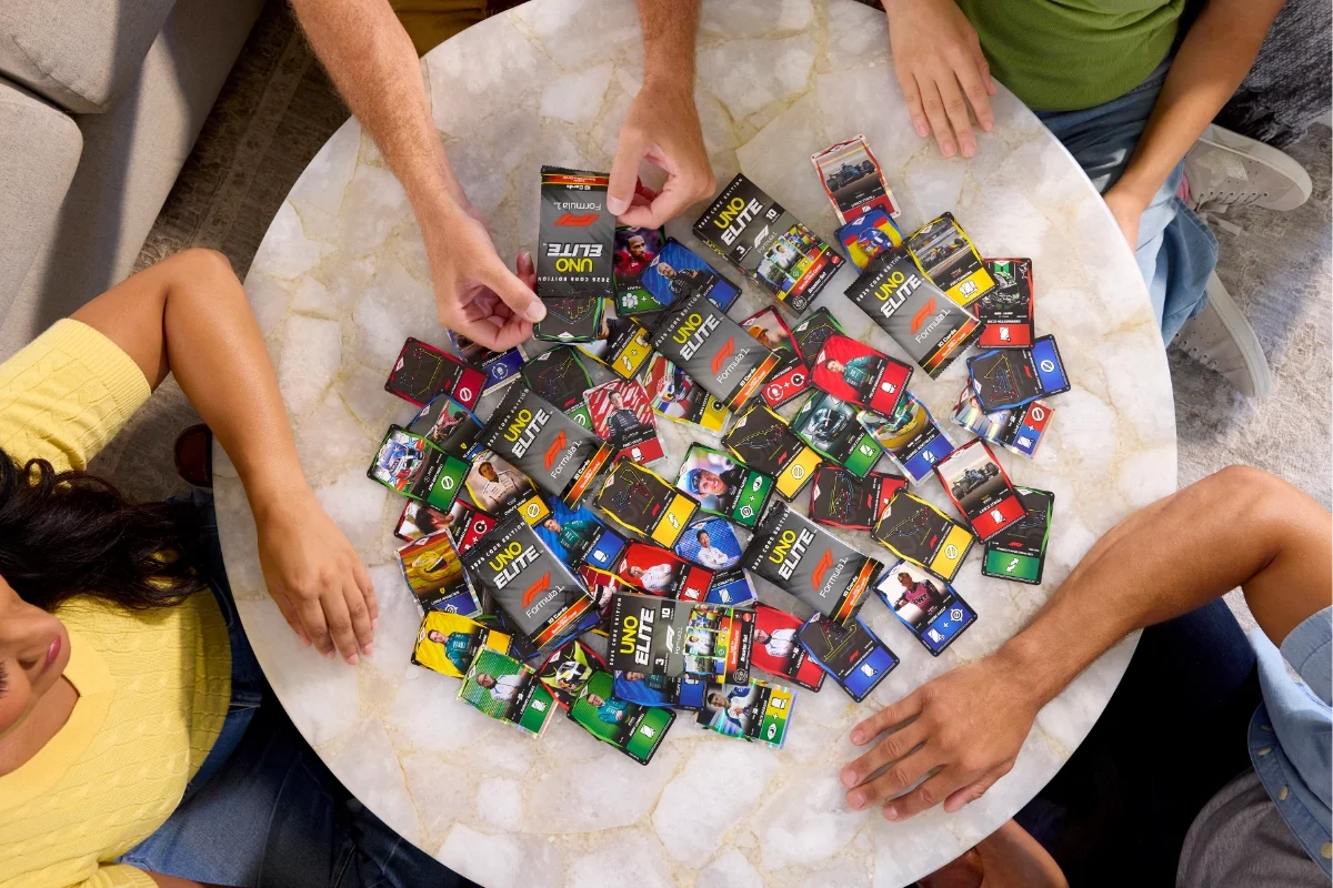Group of people playing UNO Elite Formula 1 with cards spread across a table