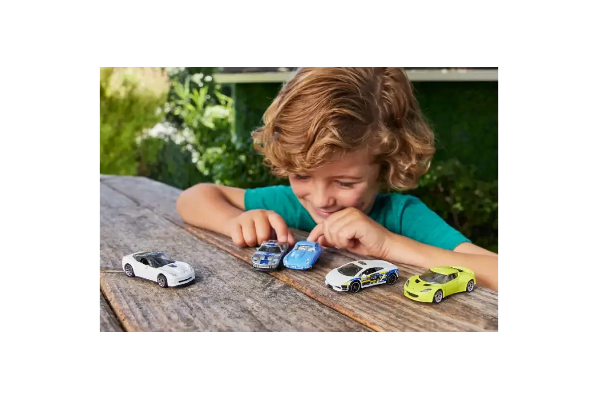 Child playing with Matchbox cars outdoors on wooden surface