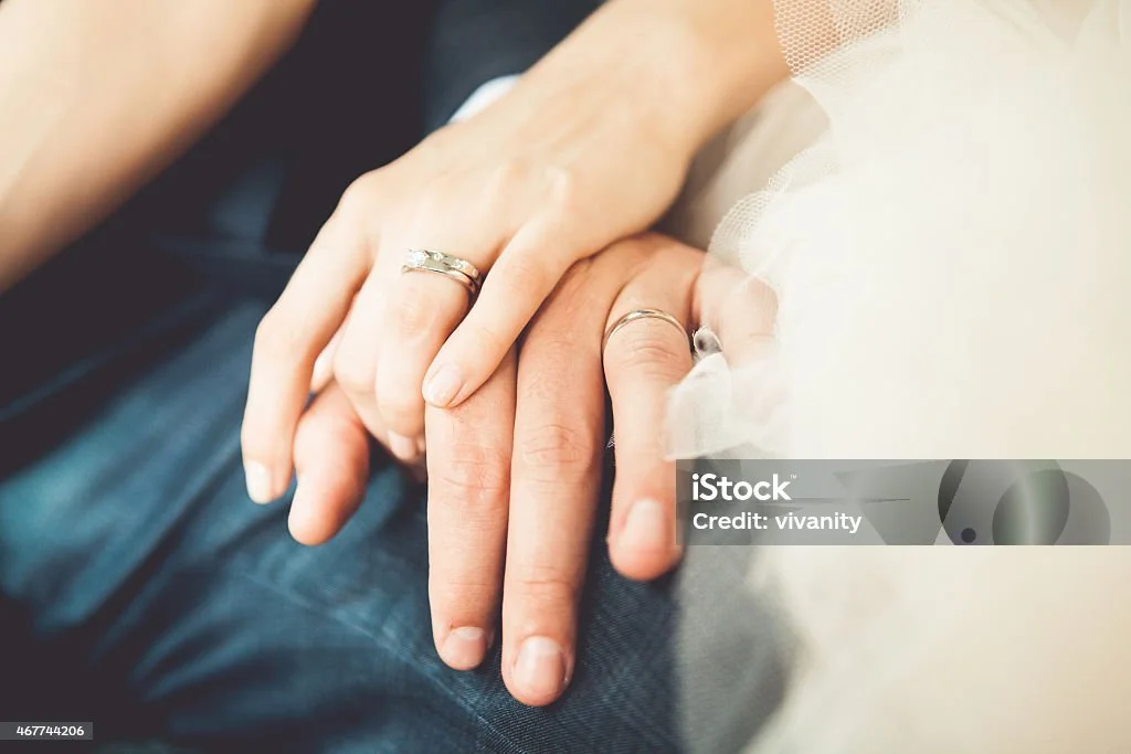 Nahaufnahme von zwei Händen, die sich berühren, mit Eheringen an den Fingern, symbolisiert Liebe und Partnerschaft.
