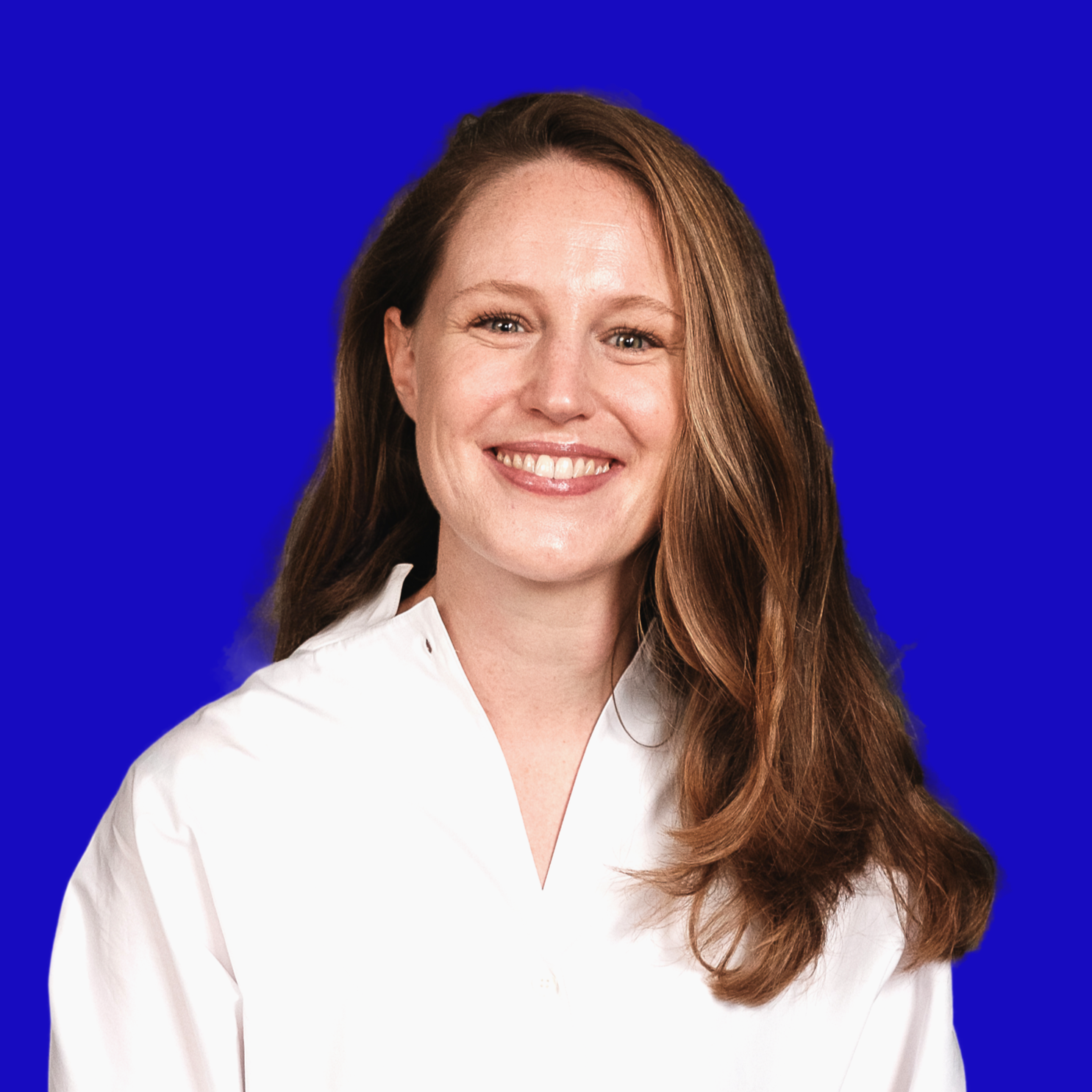 Lächelnde Frau mit braunen, lockigen Haaren in Weiß vor blauem Hintergrund.