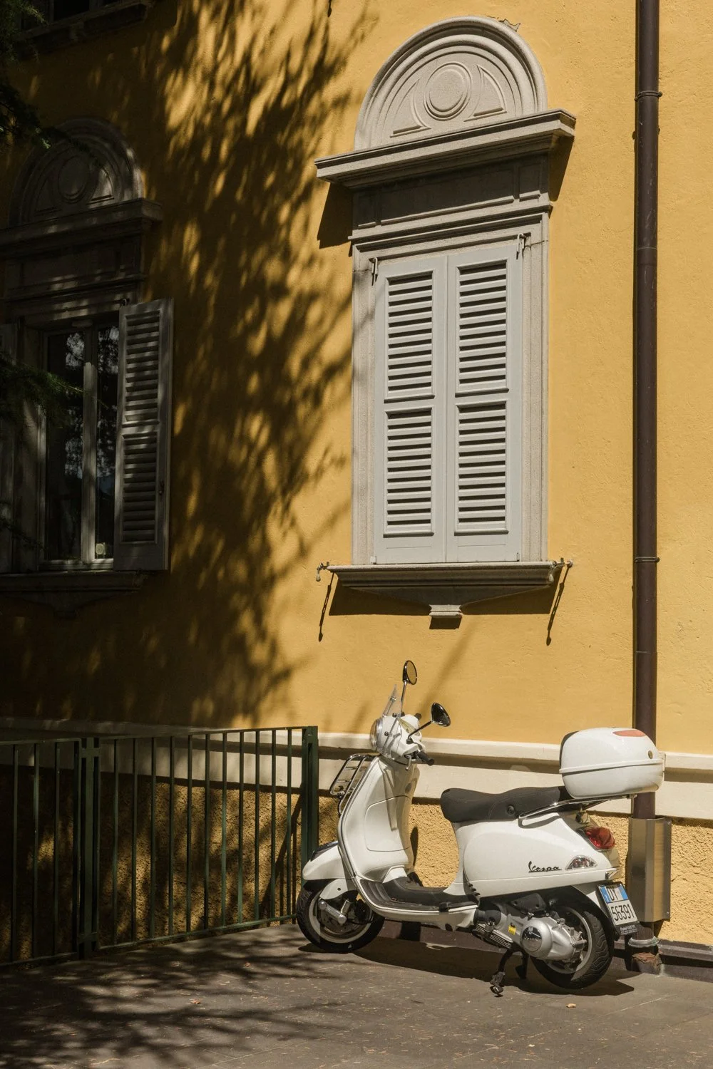 White Vespa parked against a golden stucco building in Varenna, Lake Como, Italy — Italy travel photographer Anna Hudson
