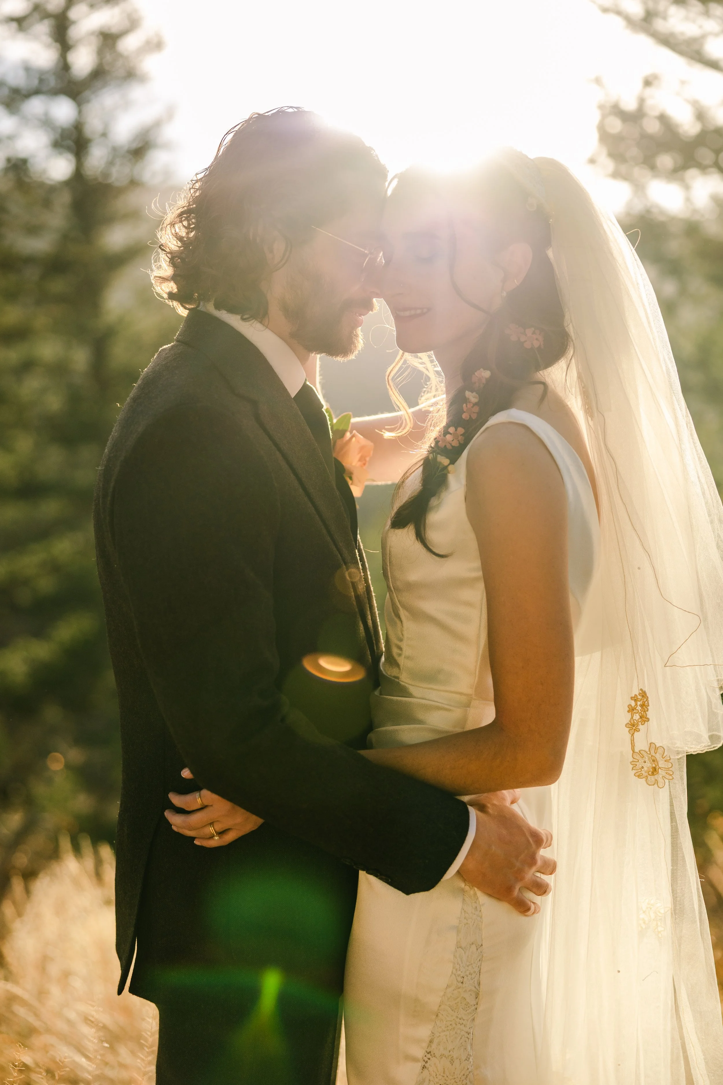 Bride and groom sharing an intimate moment surrounded by golden sun flare and pine trees at Chautauqua Park, Boulder, Colorado — elopement photographer Anna Hudson
