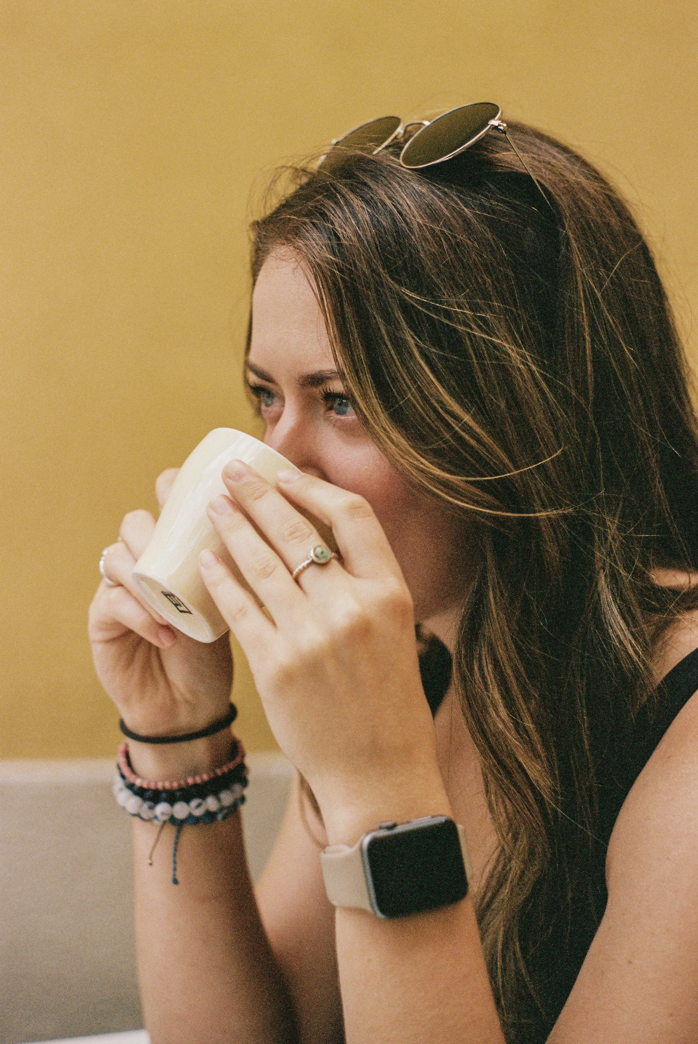 Woman sipping coffee at a café against a warm yellow wall in Lecco, Lake Como, Italy — Italy travel and branding photographer Anna Hudson