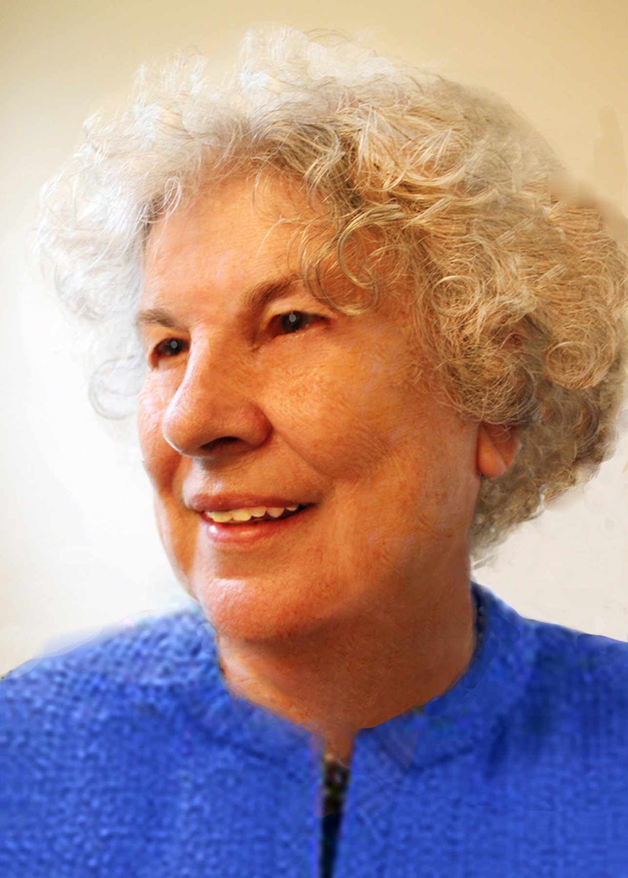Close-up of an elderly woman with curly gray hair smiling, wearing a blue textured sweater.