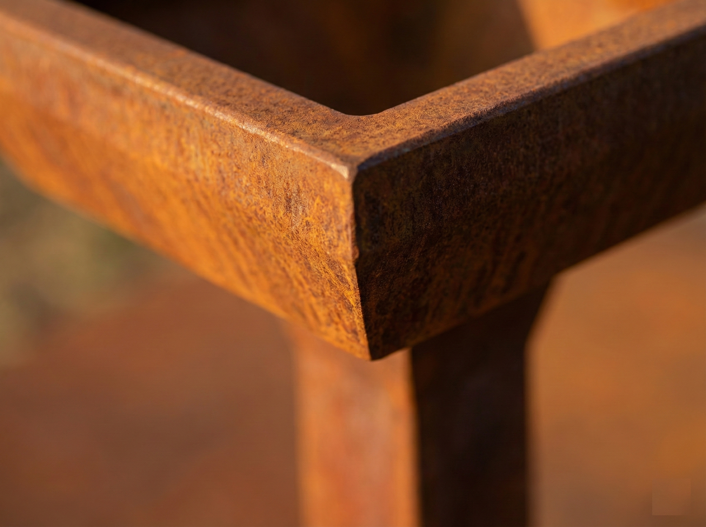 Dettaglio superficie acciaio Corten fioriera Pylon, primo piano sulla texture ruggine naturale e sulla geometria dell'angolo