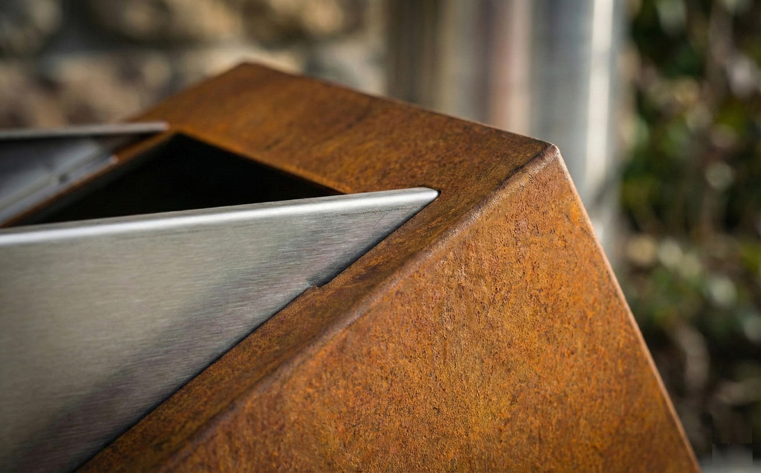 Macro texture materiali acciaio Corten e Inox: particolare della patina protettiva naturale e della giunzione di precisione tra metallo grezzo e finitura moderna