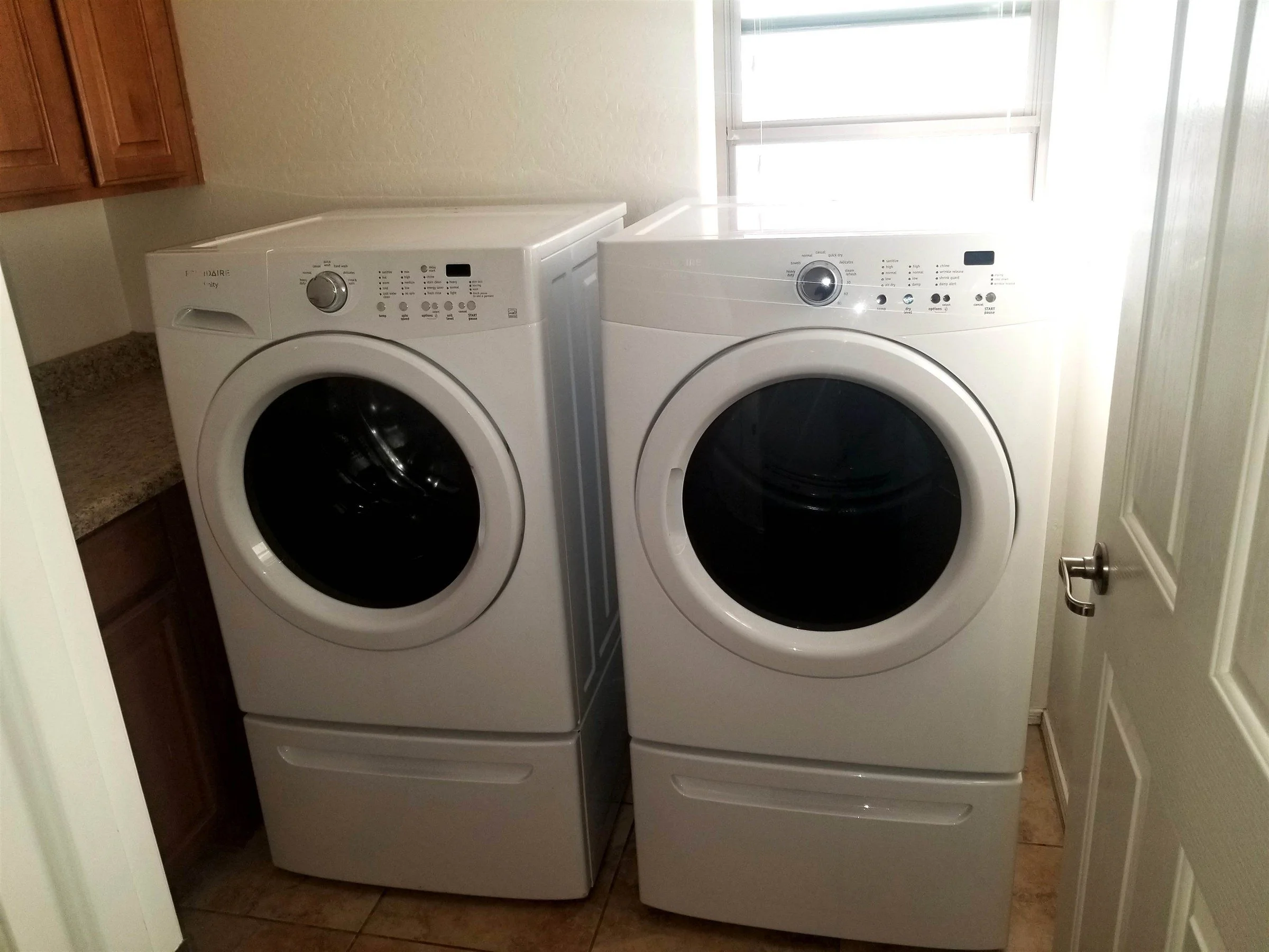 Front-load washer and dryer on pedestals, installed and leveled in a Phoenix home