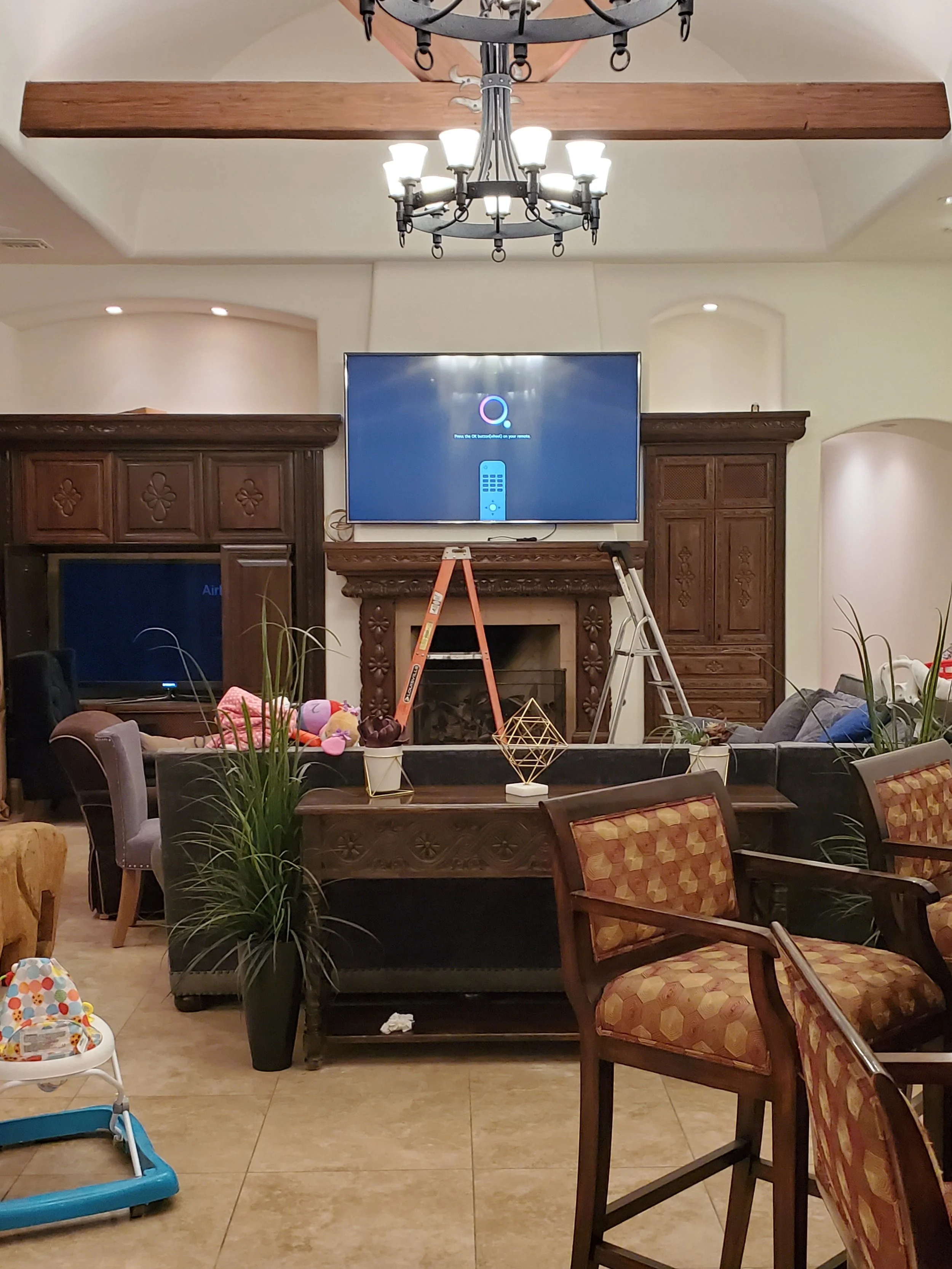 Commercial TV wall mounting above a dark wood fireplace mantel in a Phoenix community clubhouse lounge, featuring heavy-duty stud anchoring and concealed cable integration.