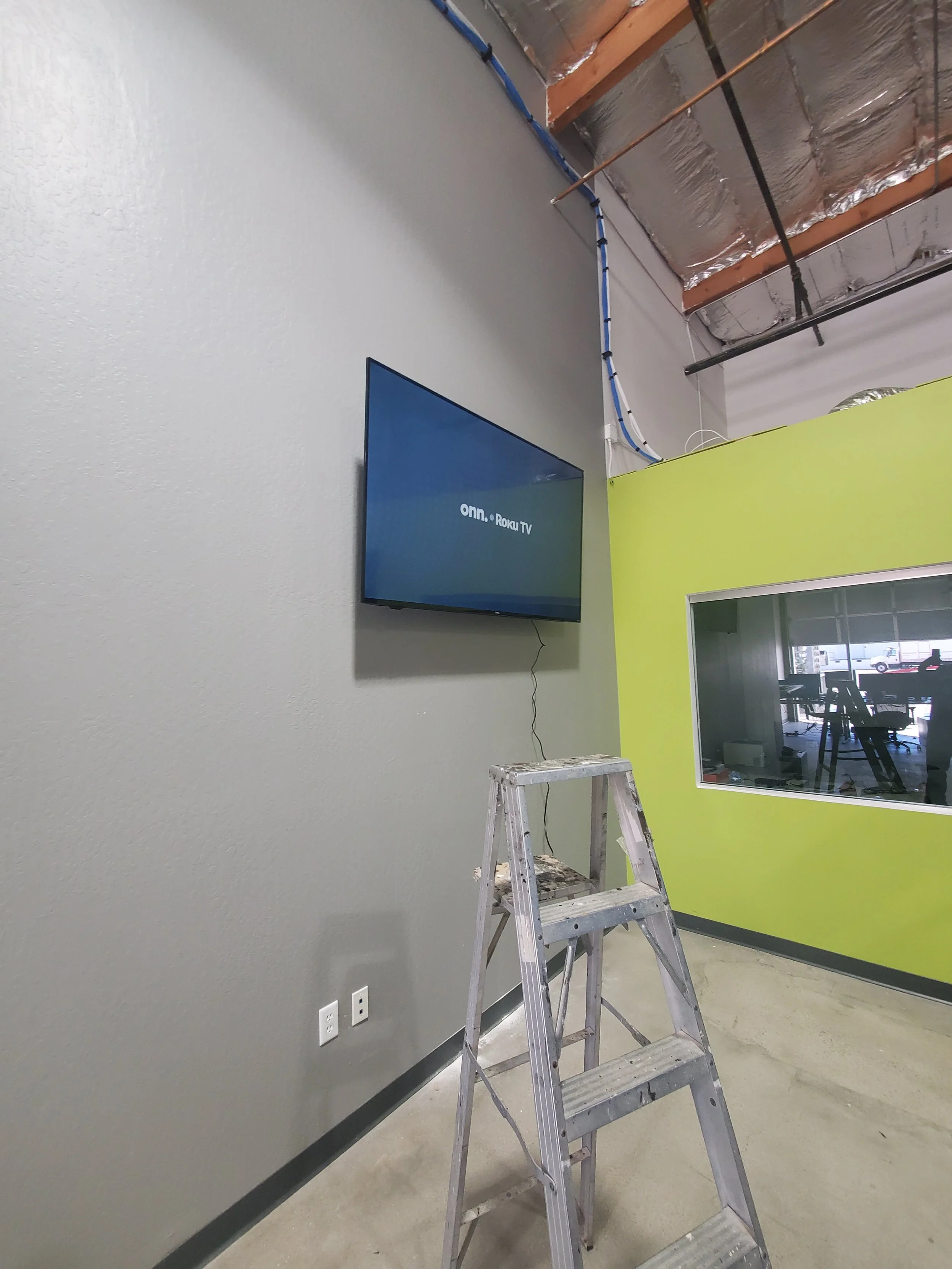 High-wall commercial TV mounting in a Phoenix industrial office facility, installed with heavy-duty structural anchors and clean conduit cable management.