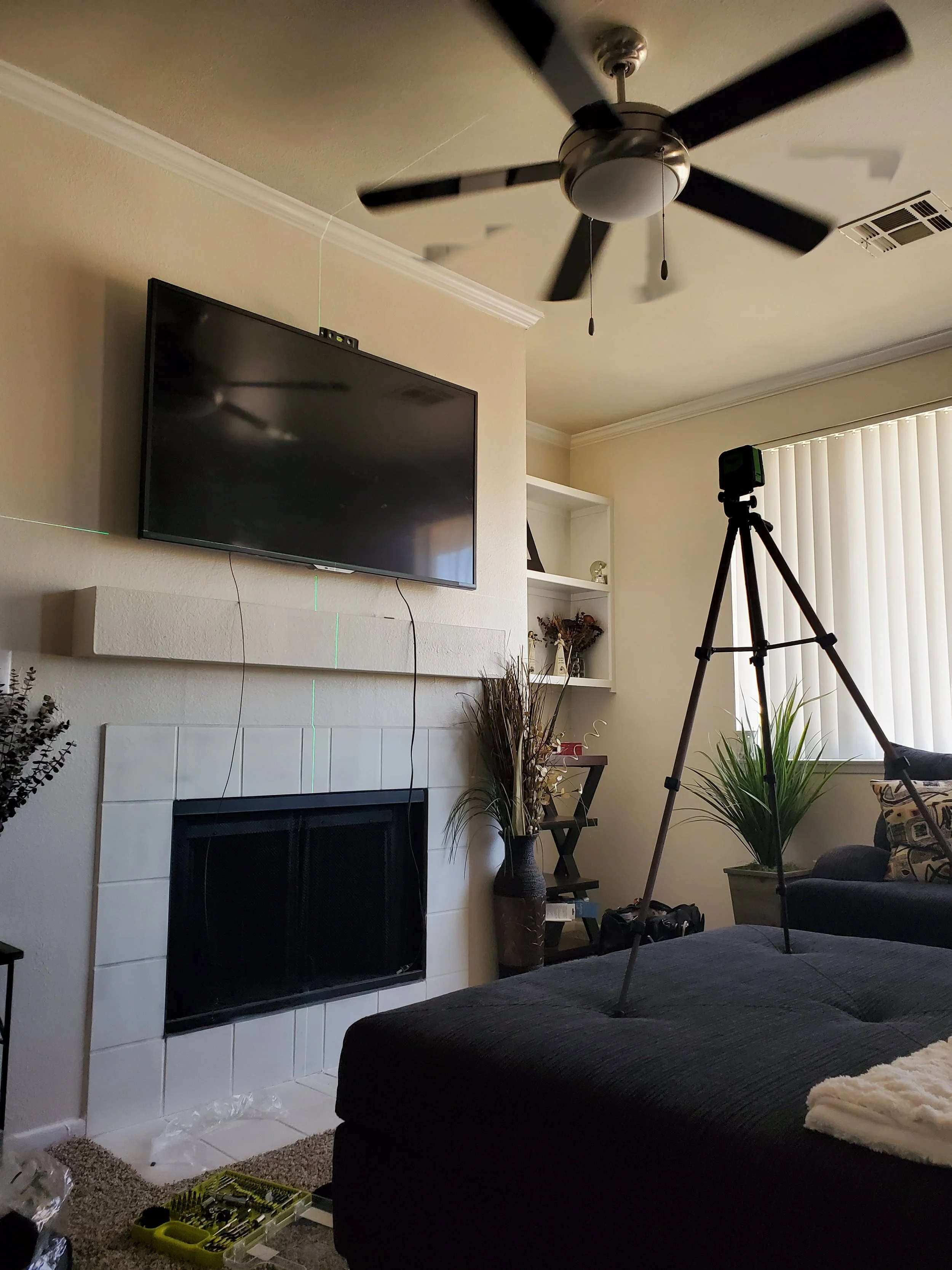 Living room flat screen mounted above a stone fireplace mantle in a Phoenix open-concept space, featuring hidden wire management and vaulted ceiling stud anchoring.