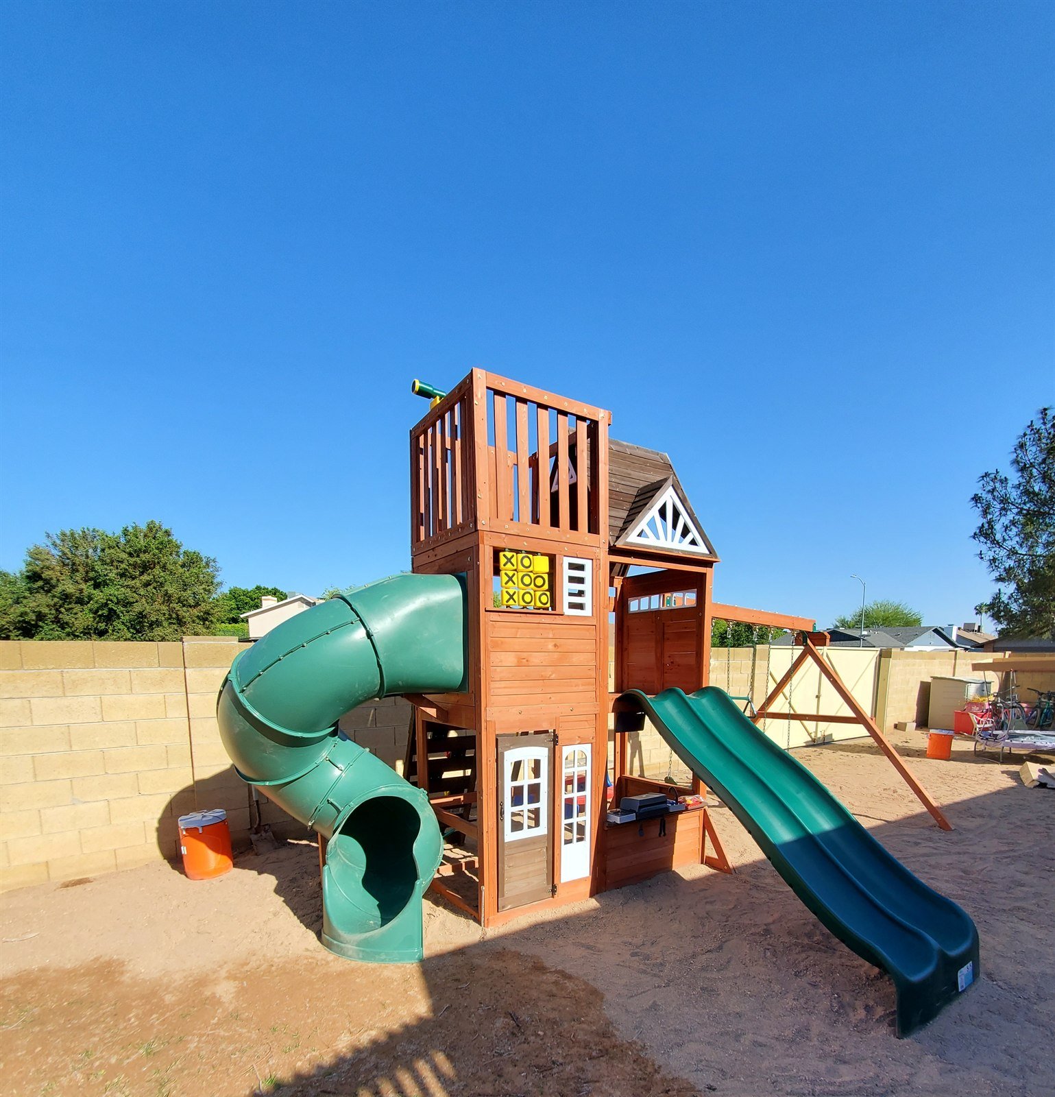 Cedar playset with green tube slide and wave slide assembled in a Gilbert backyard