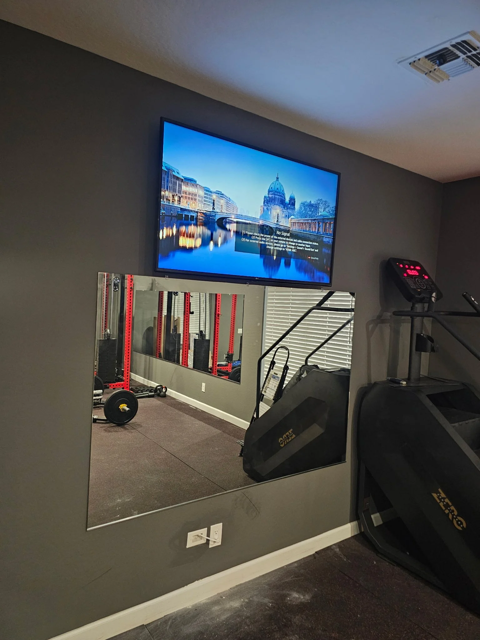 TV mounted over a frameless mirror in a Phoenix, AZ home gym with wires fully concealed
