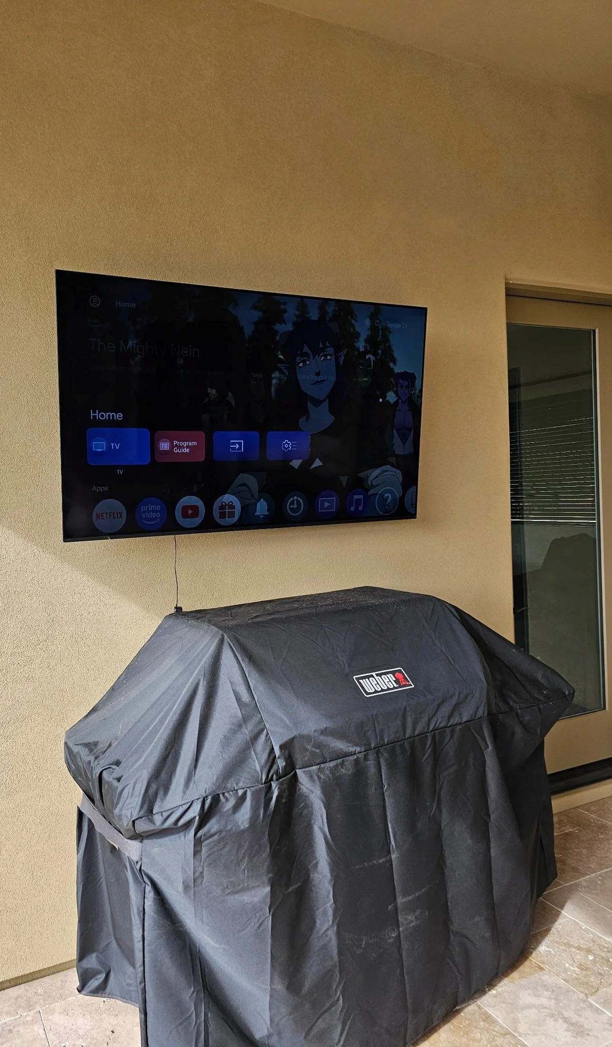Outdoor TV mounted on a stucco patio wall above a grill in Phoenix