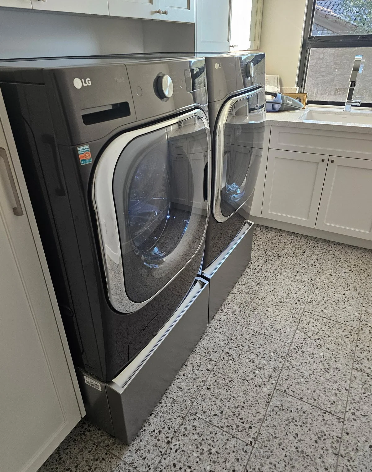 LG front-load washer and dryer installed on pedestals by Helping Hands appliance installers in a Phoenix laundry room