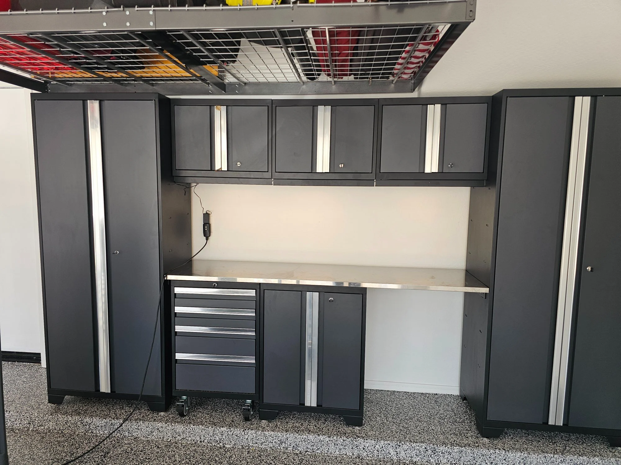 Black steel garage cabinet system with a workbench and an overhead storage rack, organized in a Sun City, AZ garage