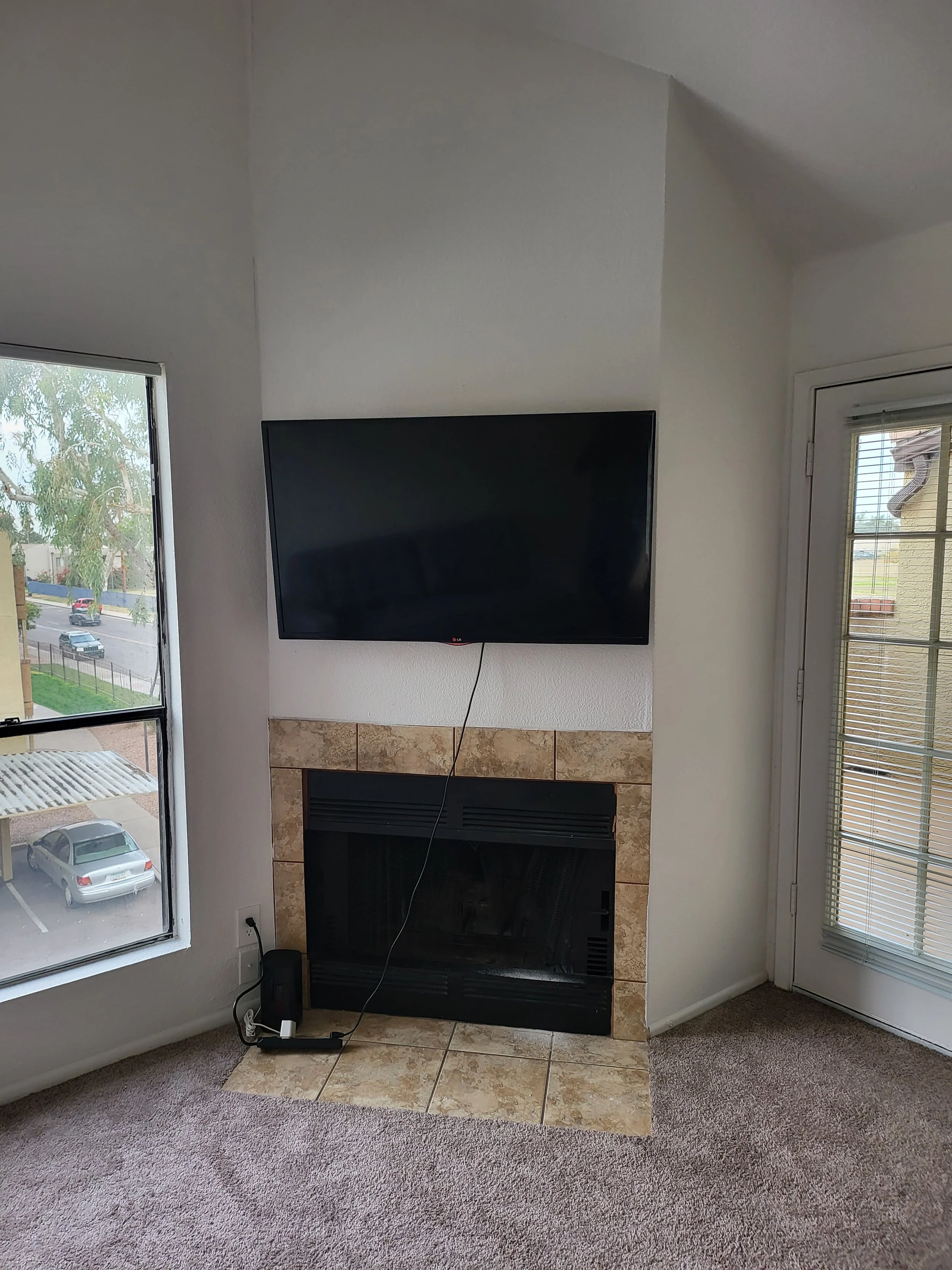 Professional high-wall TV mounting above a fireplace on drywall in a Phoenix, AZ vaulted living room with complete in-wall wire concealment.