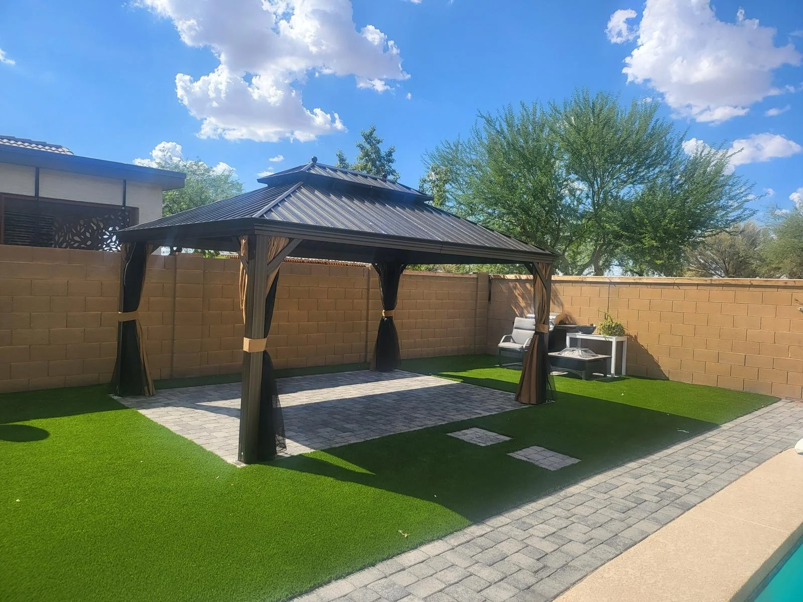 Black hardtop metal gazebo installed by Helping Hands gazebo builders in a Phoenix backyard by the pool