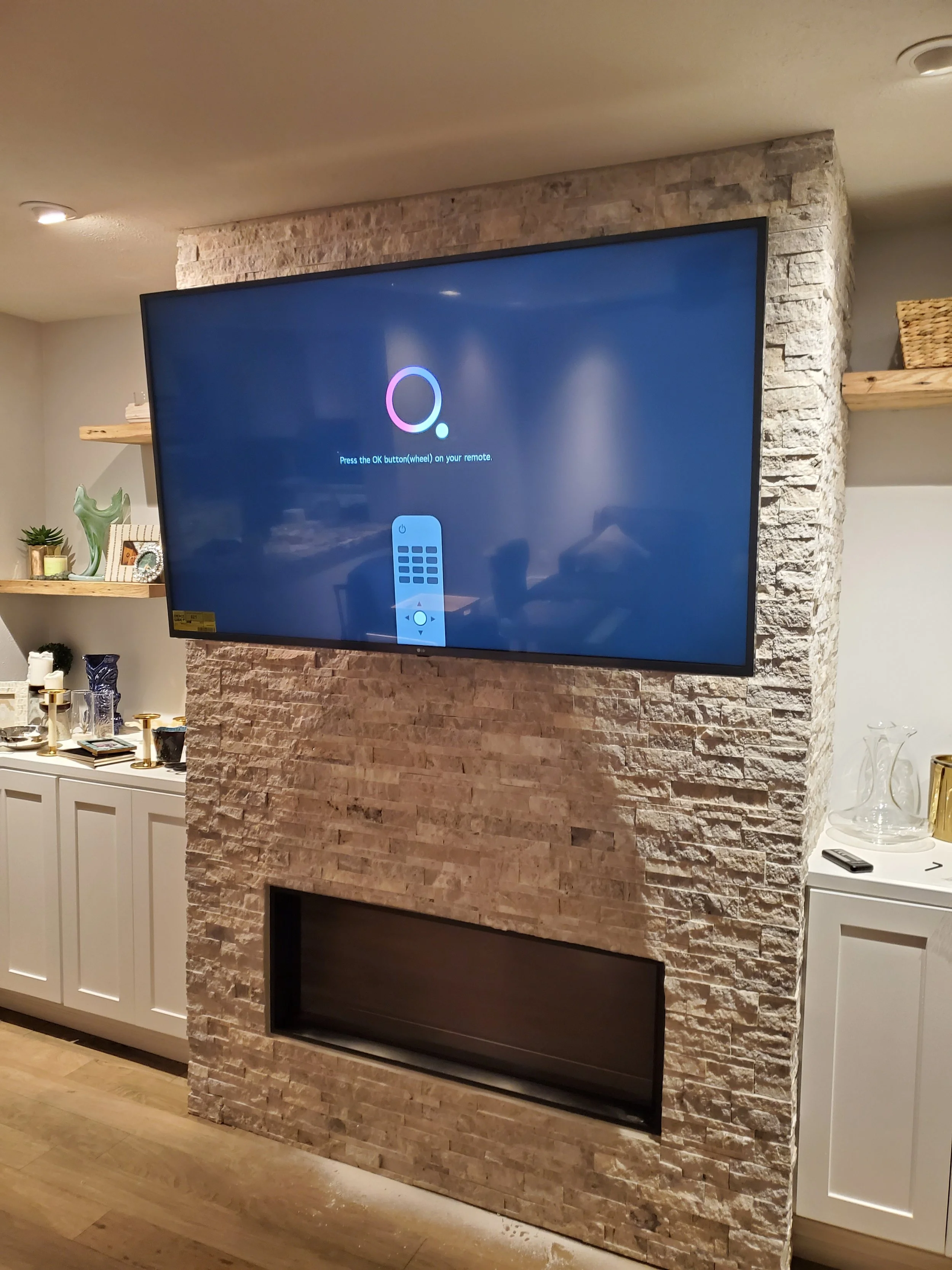 Professional TV wall mounting above a stacked stone fireplace in Phoenix, AZ with concealed wiring and heavy-duty stone anchoring.
