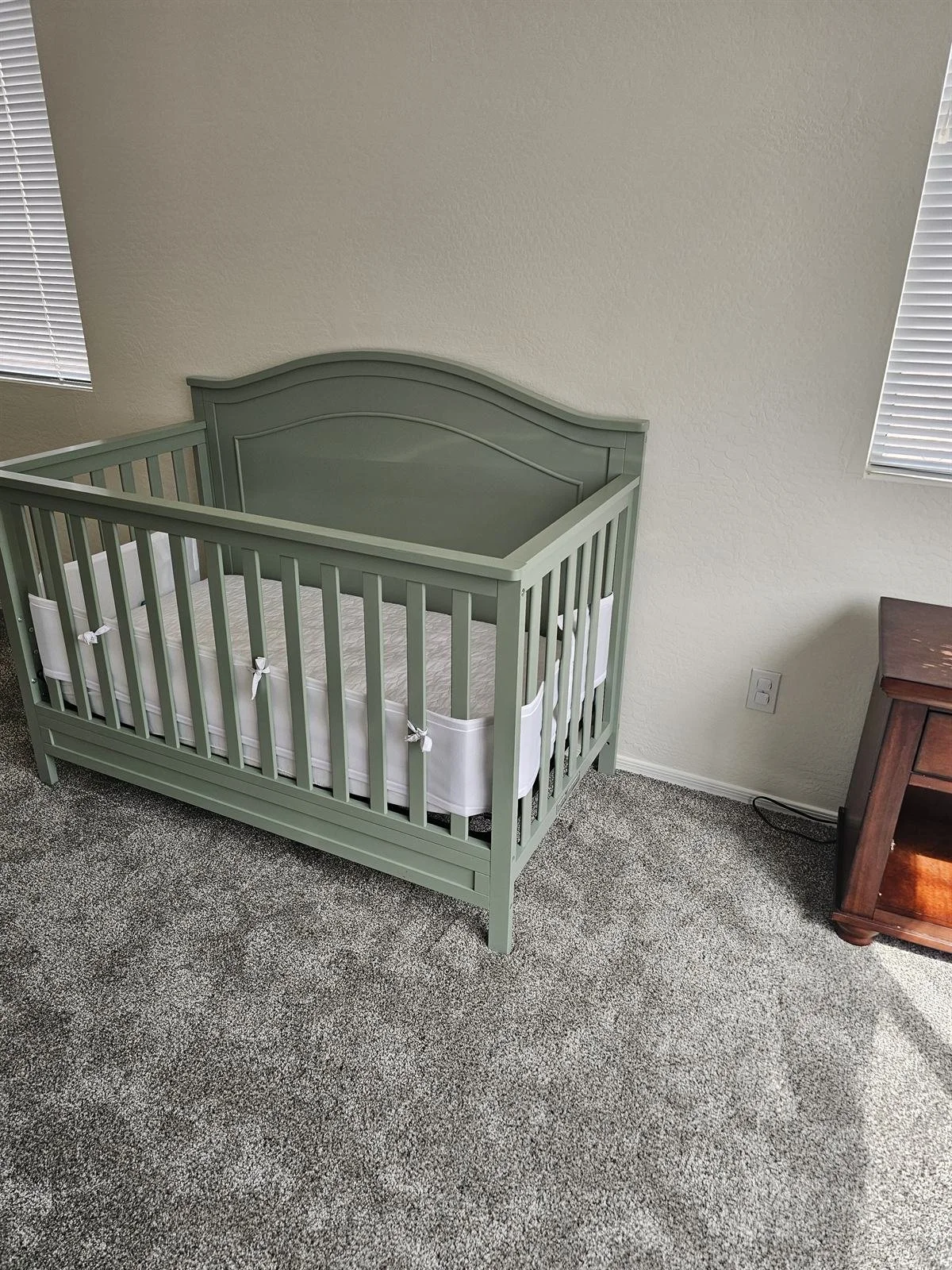 Sage green convertible crib assembled in a Phoenix nursery