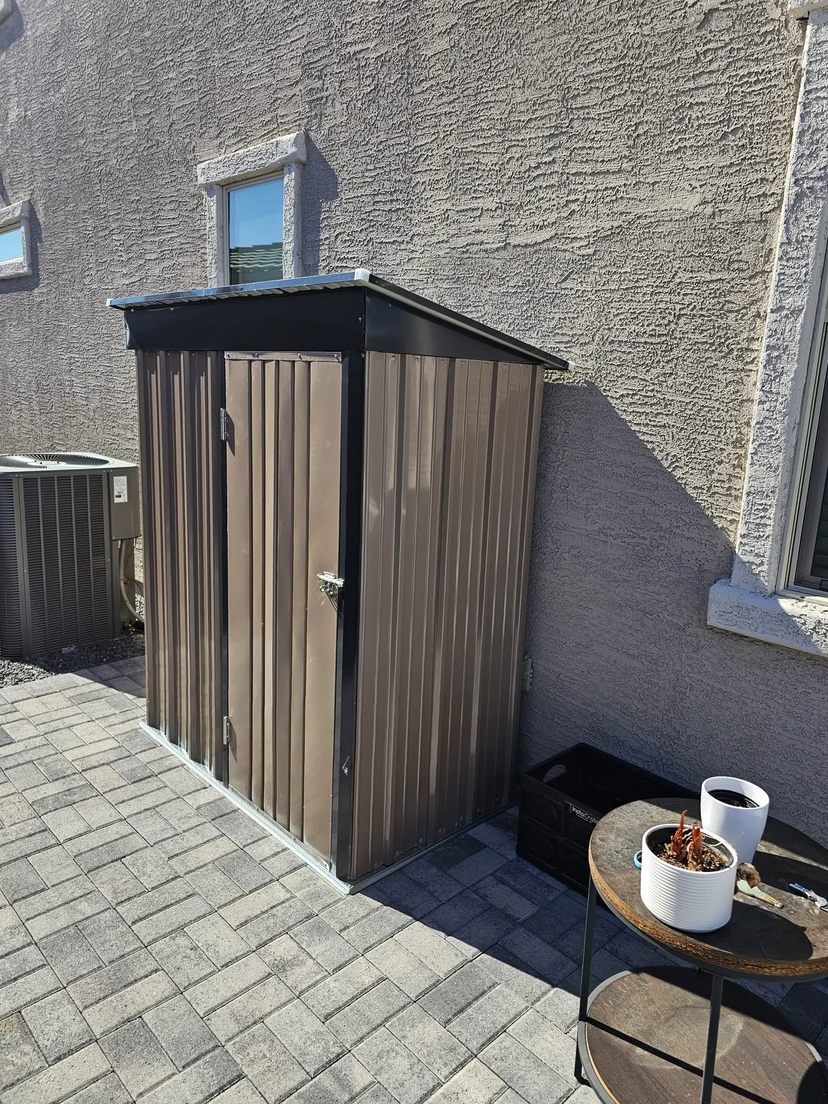 Small brown metal lean-to storage shed assembled beside a house in the Phoenix, AZ area by Helping Hands Household Solutions