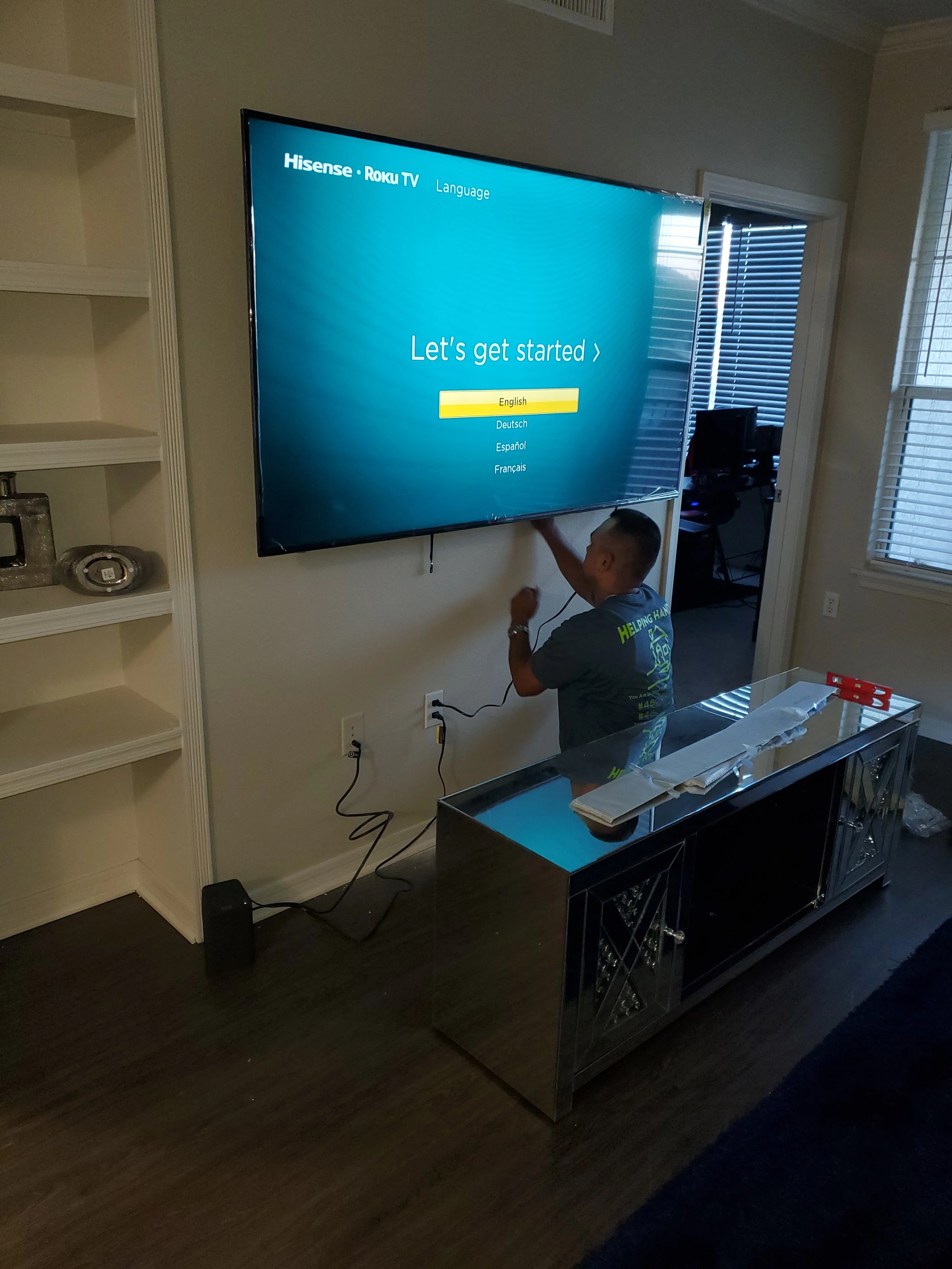 Sleek wall-mounted flat screen positioned above a wooden media console in a Phoenix home entertainment nook, featuring custom in-wall wire routing next to built-in display shelving.