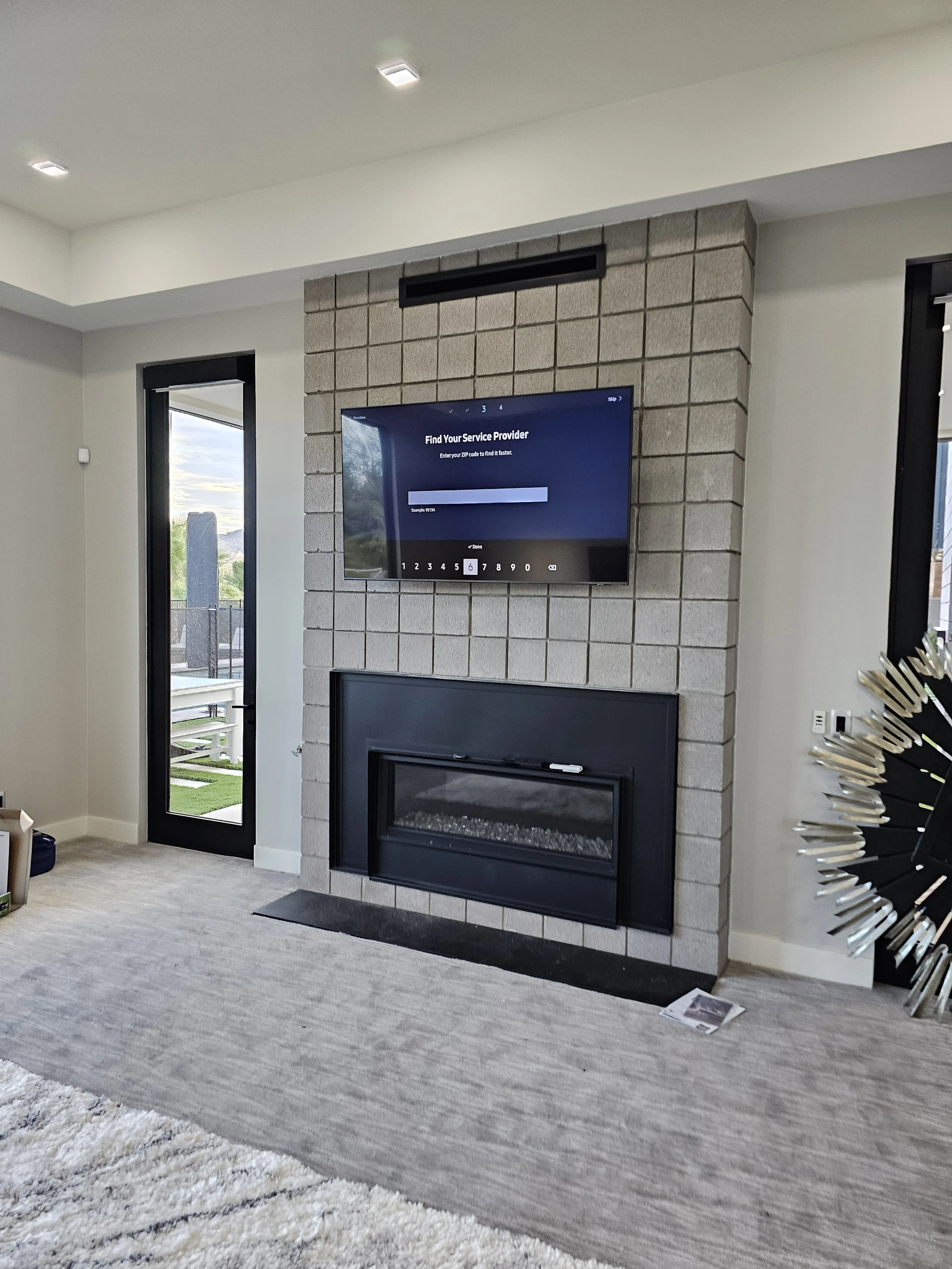 Professional TV wall mounting above a custom concrete-tiled electric fireplace in Phoenix, AZ with complete in-wall wire concealment and heavy-duty anchoring.