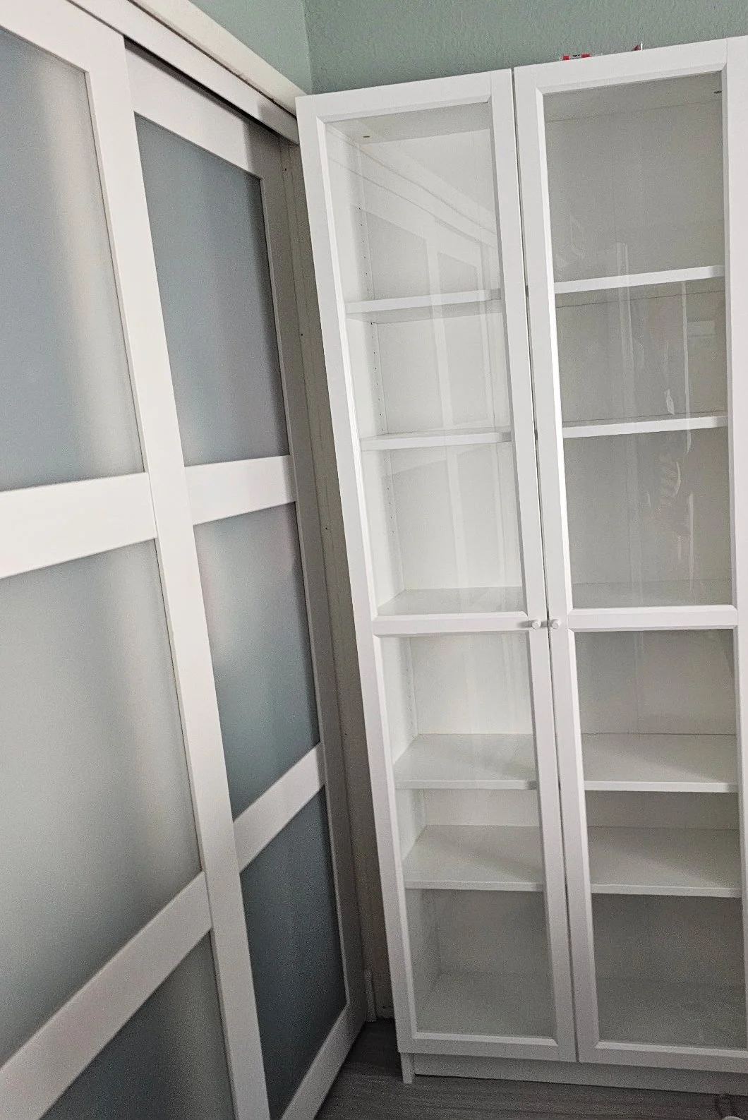 White IKEA BILLY bookcase with OXBERG glass doors assembled in a Tempe bedroom