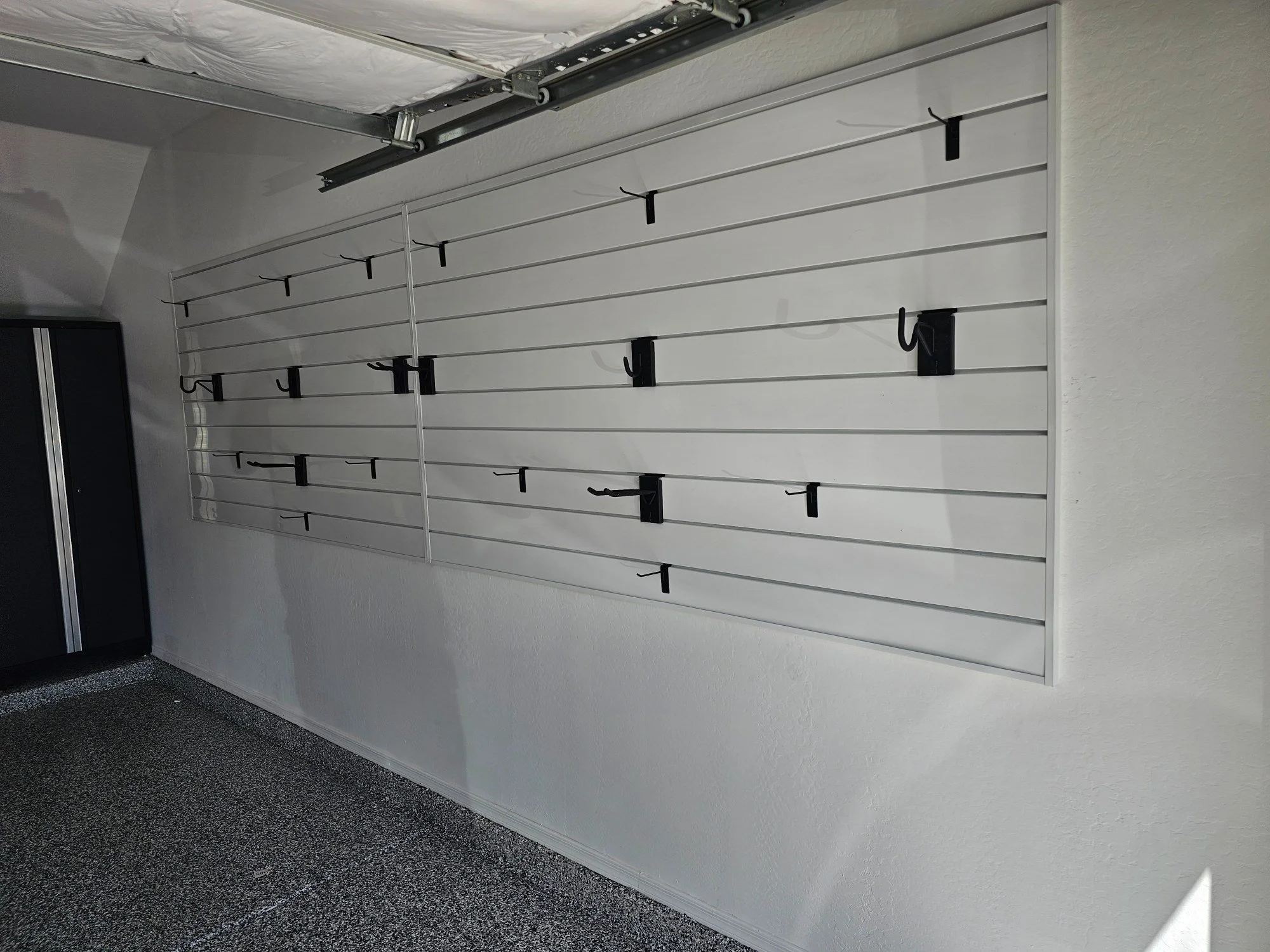 White slatwall panels with black hooks installed on a garage wall in Sun City, AZ